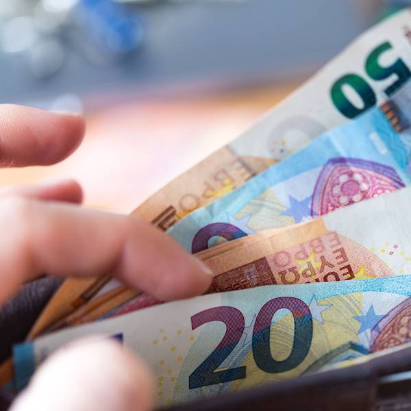 Eine Frau hält eine Geldbörse mit Banknoten in der Hand.