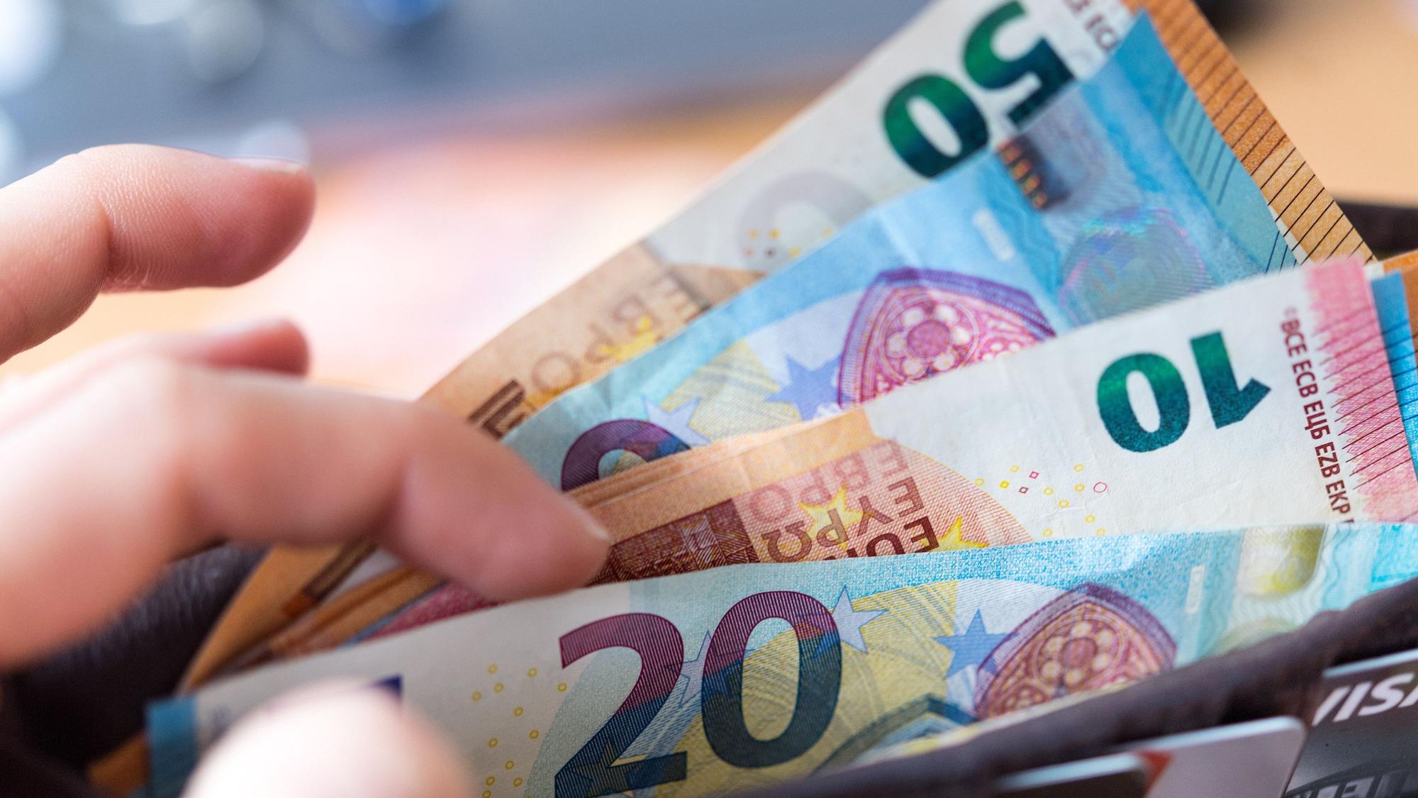 Eine Frau hält eine Geldbörse mit Banknoten in der Hand.