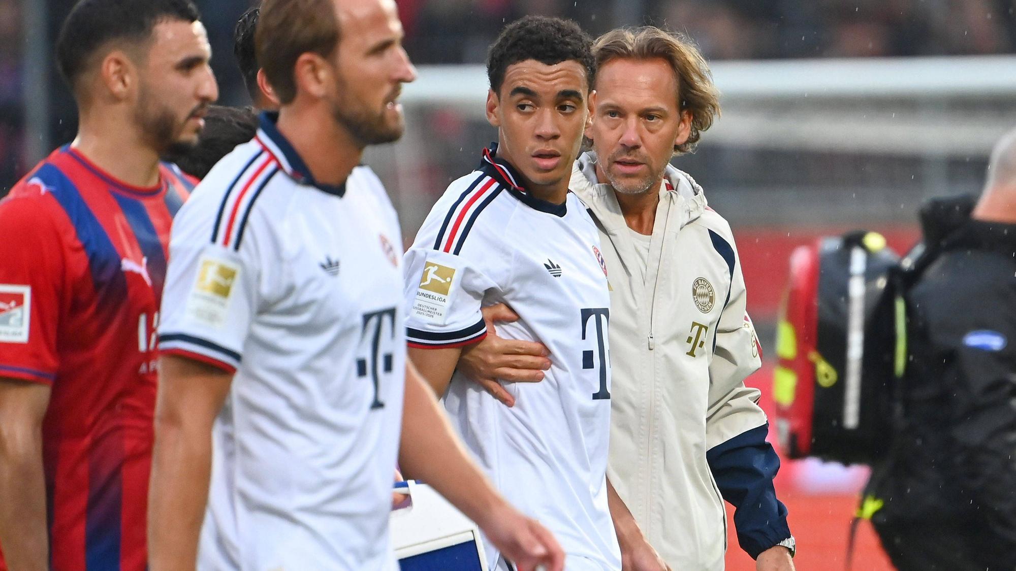 Jamal MUSIALA Bayern Muenchen bricht erneut zusammen,Ohnmacht, wird von Dr.Peter UEBLACKER Mannschaftsarzt FCB vom Platz gefuehrt, li:Harry KANE Bayern Muenchen. Fussball Testpiel / 1.FC Heidenheim - FC Bayern Muenchen 2-5 am 18.08.2025 , VOITH ARENA. *** Jamal MUSIALA of Bayern Munich collapses again,faints, is led off the field by Dr. Peter UEBLACKER, FCB team doctor featuring Harry KANE, Bayern Munich soccer friendly match: FC Heidenheim 1, FC Bayern Munich 2-5 on August 18, 2025, at VOITH ARENA