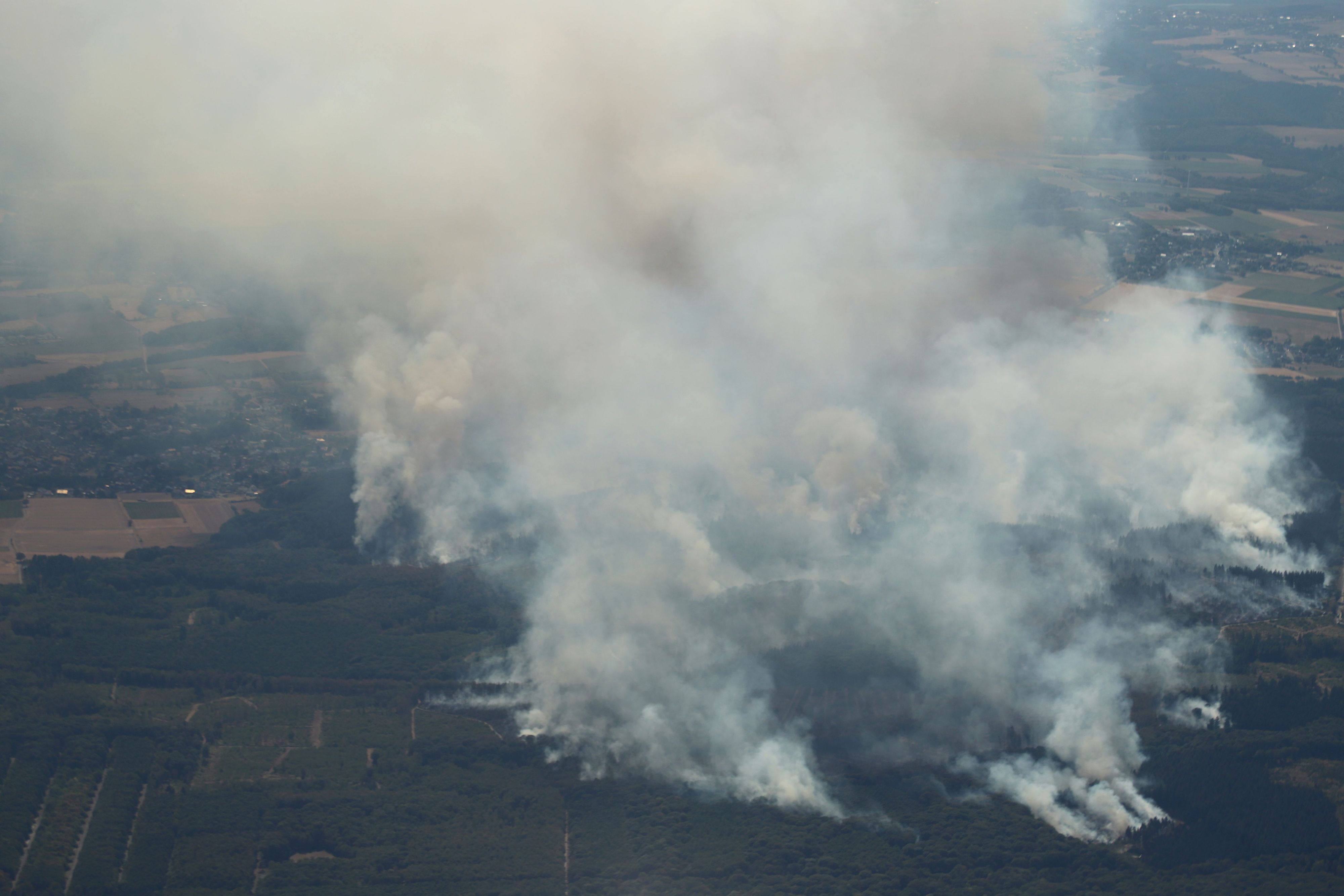 14.08.2026, Nordrhein-Westfalen, Düren: Rauch eines Waldbrands steigt über dem Hürtgenwald auf (Aufnahme aus einem Flugzeug). Mehrere Hundert Hektar Waldfläche stehen in Flammen. Foto: Sascha Thelen/dpa +++ dpa-Bildfunk +++
