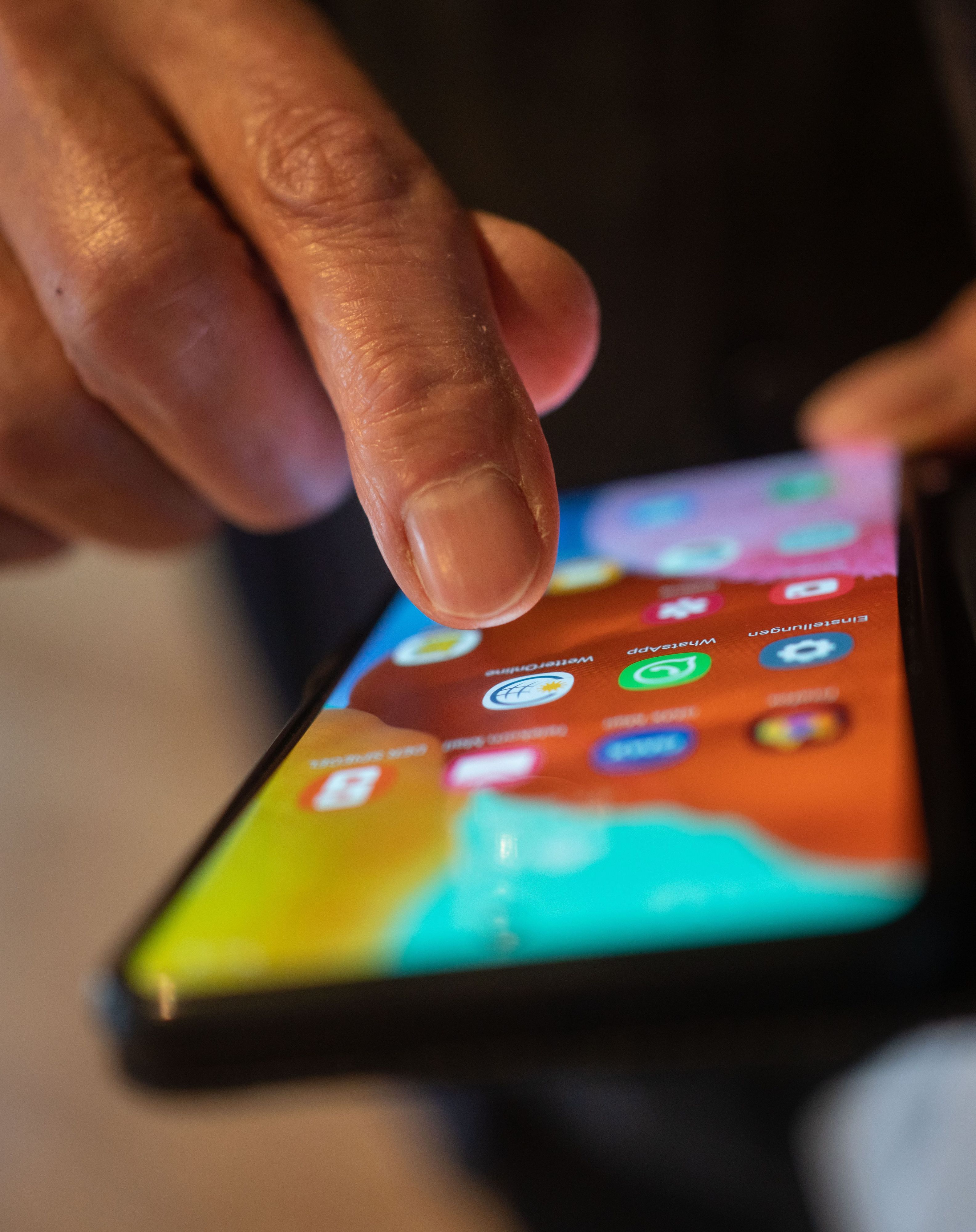 Ein Mann tippt auf seinem Smartphone, um eine App zu starten.