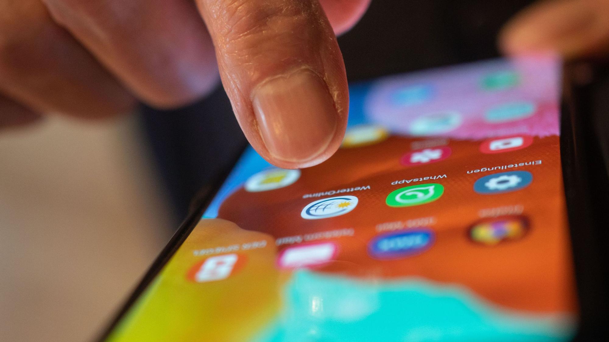 Ein Mann tippt auf seinem Smartphone, um eine App zu starten.