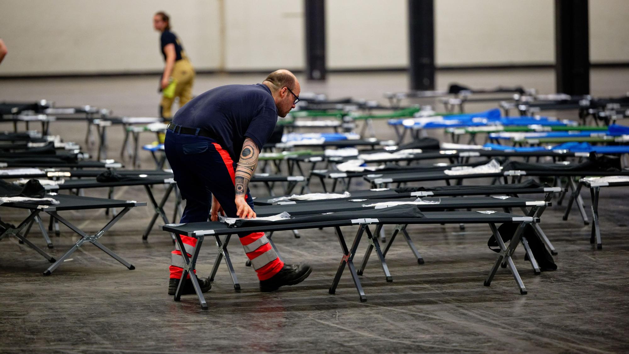 28.06.2026, Nordrhein-Westfalen, Köln: Kräfte des Malteser-Hilfsdienstes bauen im Notfallversorgungszentrum der Feuerwehr Köln in einer gekühlten Messehalle Feldbeten auf. Foto: Henning Kaiser/dpa +++ dpa-Bildfunk +++