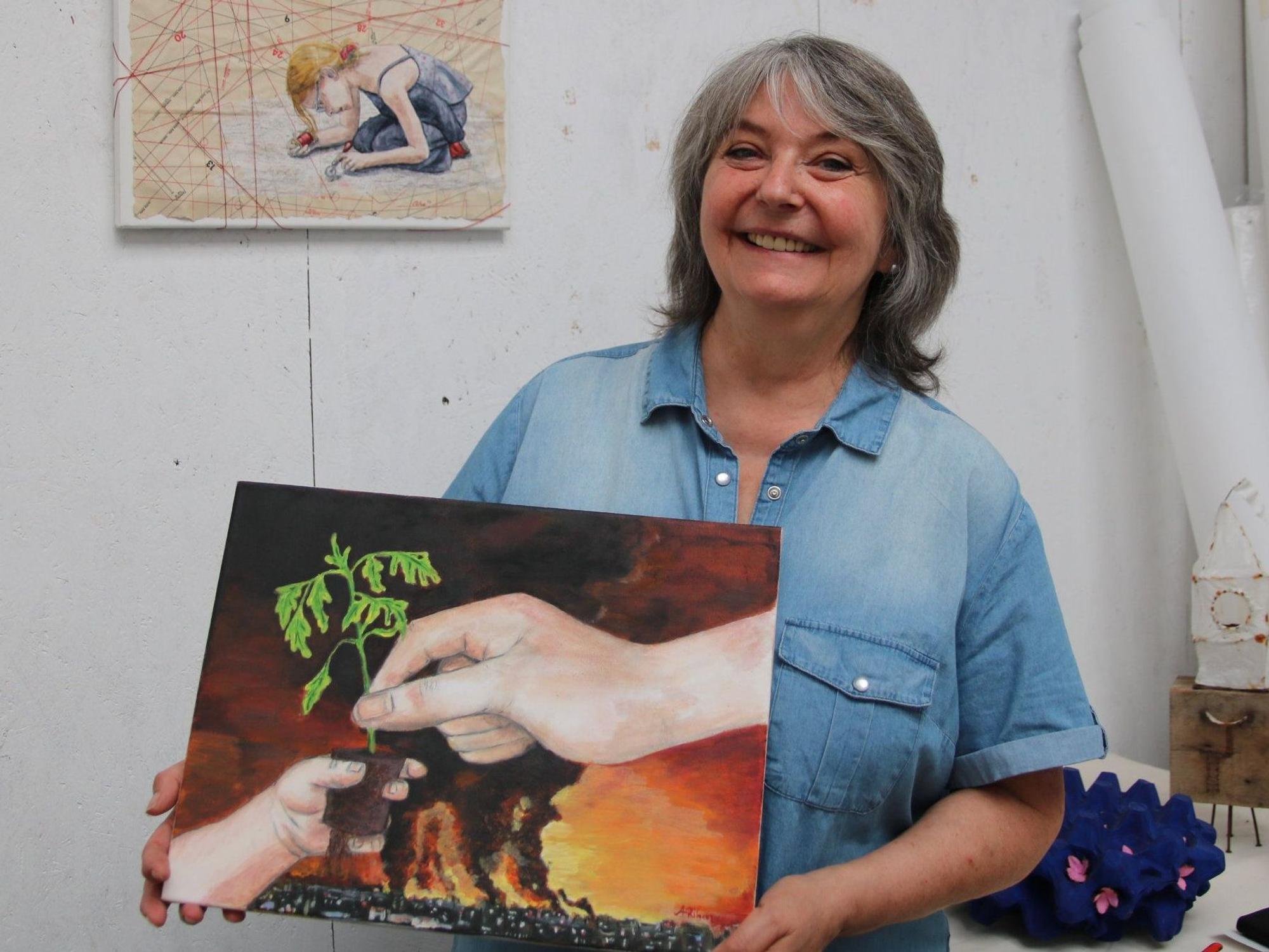 Eine Frau hält eines ihrer Kunstwerke in den Händen.
