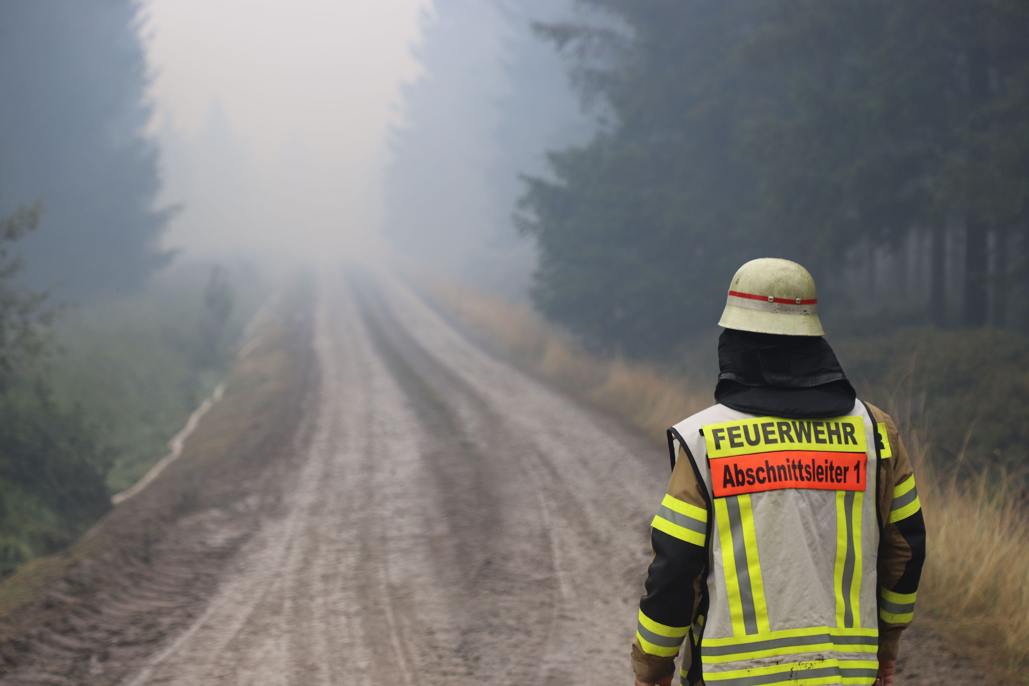 Ein Feuerwehrmann steht auf einem Weg in einem verqualmten Waldstück in der Nähe des Ortsteils Surbrot. Im belgischen Naturschutzgebiet Hohes Venn dauert der Kampf gegen die Flächenbrände an.
