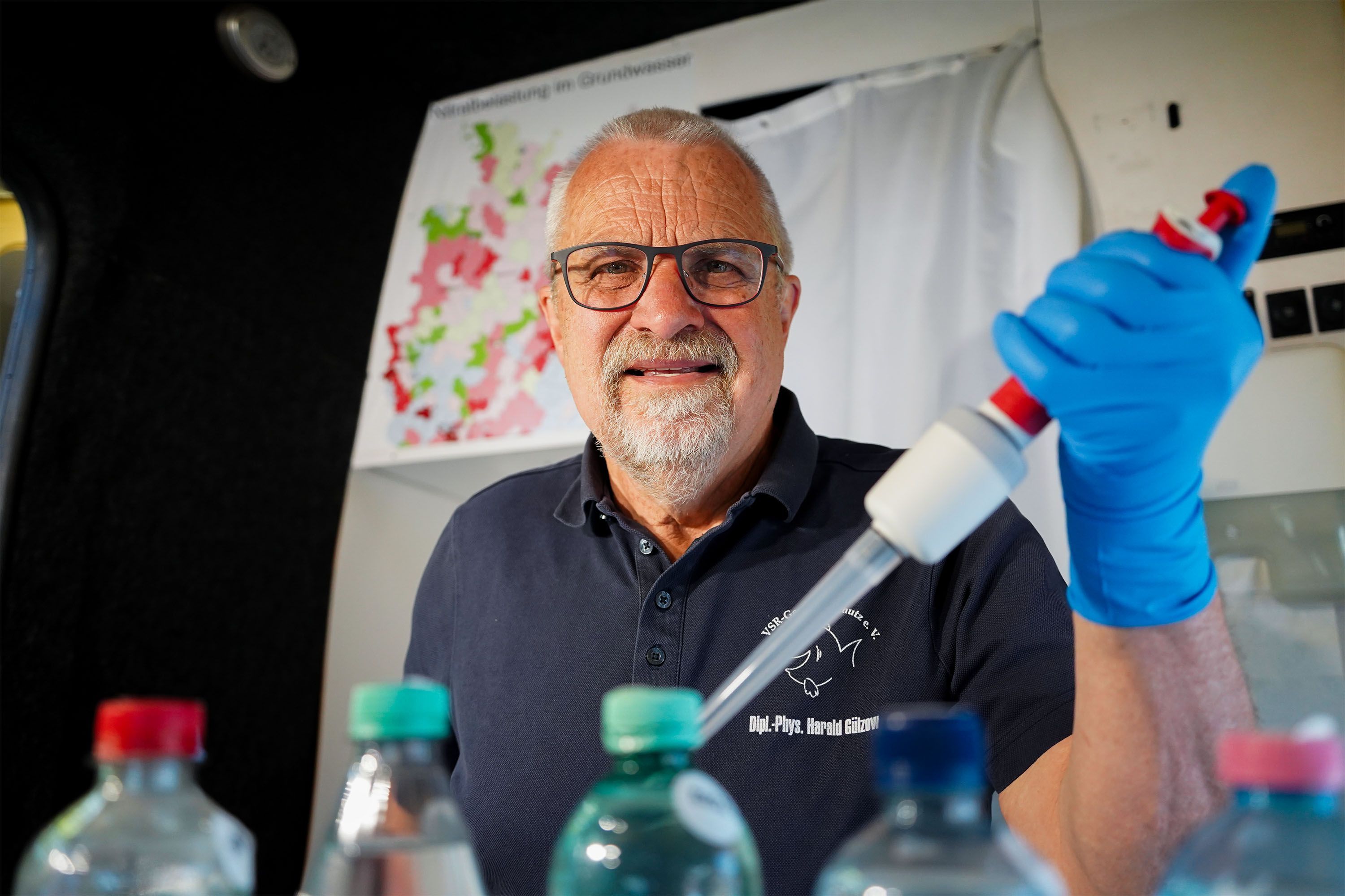 Harald Gülzow analysiert eine Brunnenwasserprobe im Labormobil des VSR-Gewässerschutzes mit einer großen Pinzette.