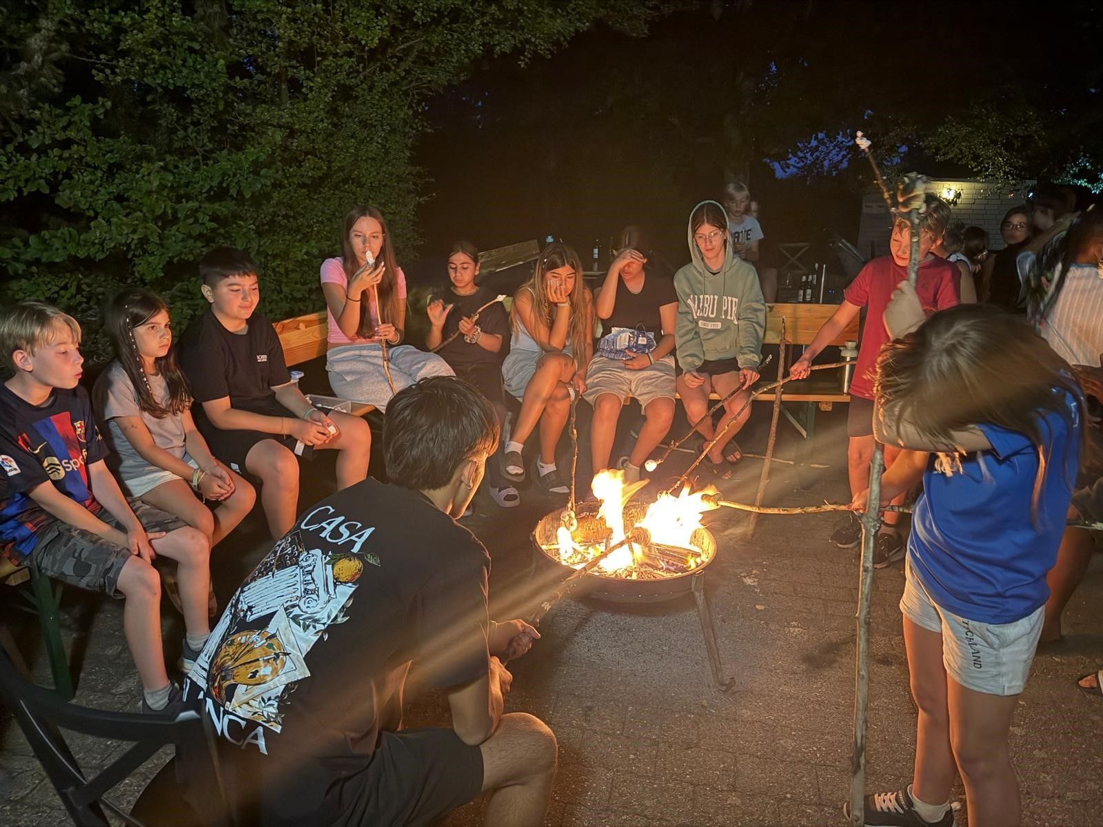Kinder backen Stockbrot an einem Lagerfeuer.