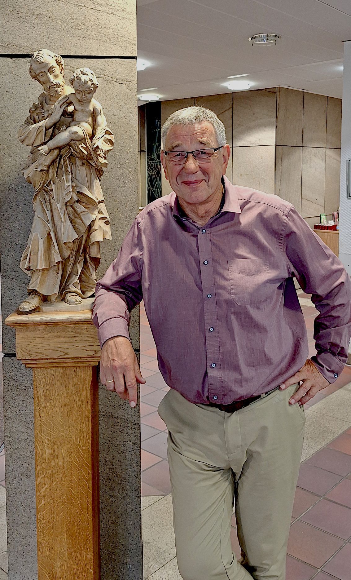 Ein Mann steht neben einer Figur des heiligen Josef.