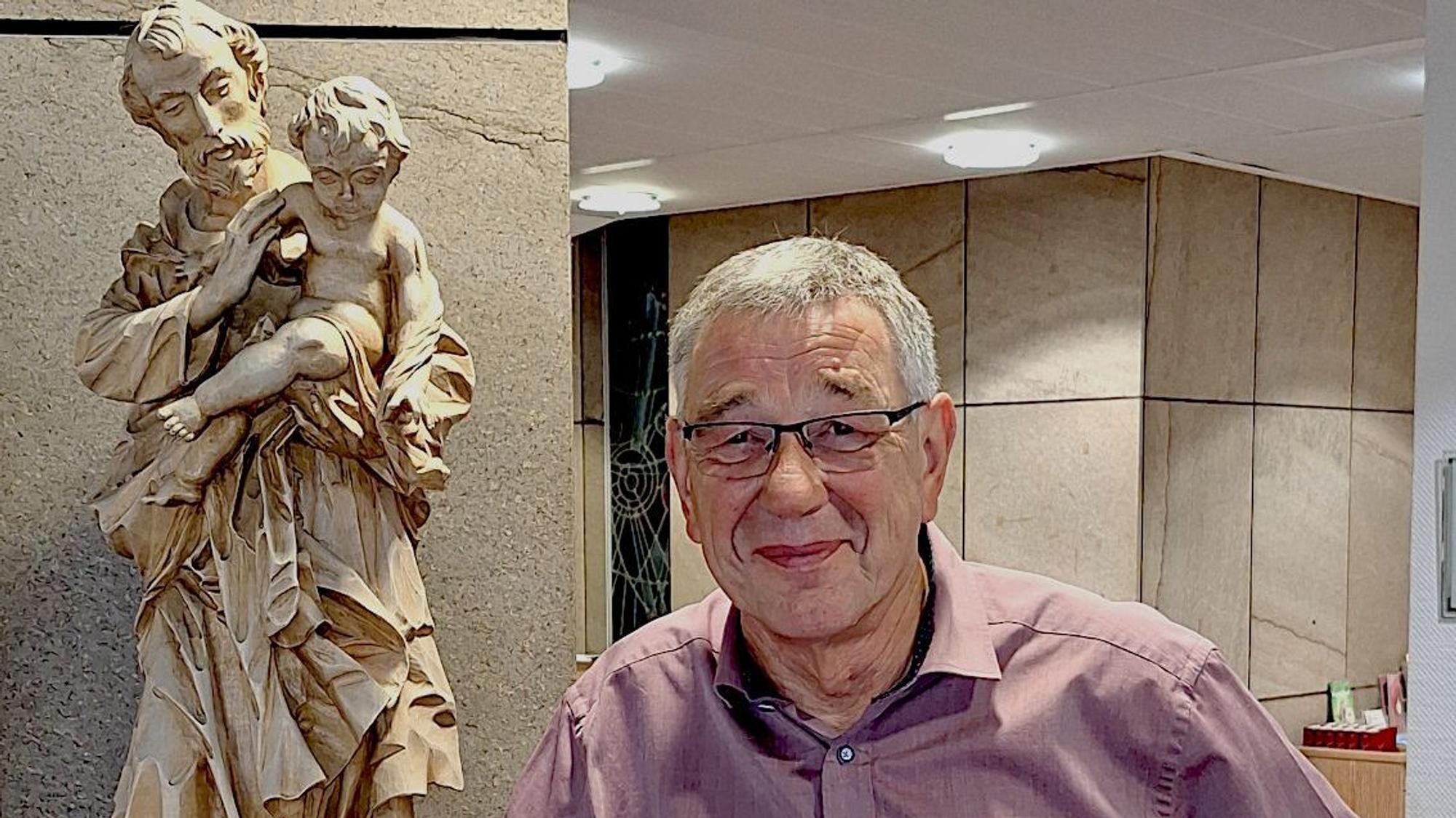 Ein Mann steht neben einer Figur des heiligen Josef.