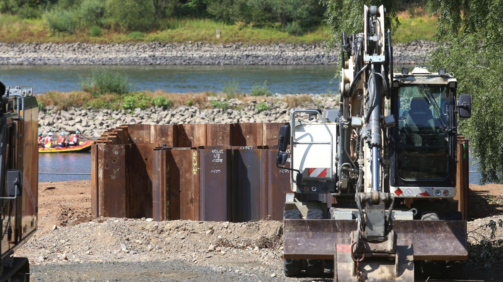 Ein Bagger neben Baugruben, im Hintergrund der Rhein.