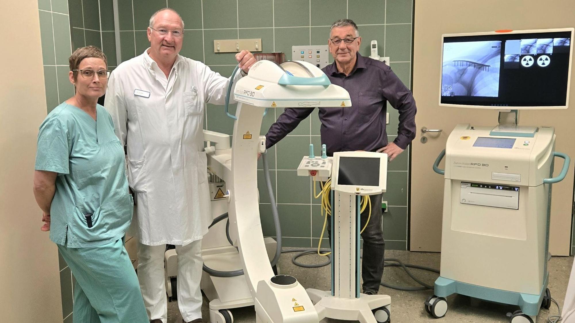 Zwei Männer und eine Frau stehen an einem Röntgengerät, das im Operationssaal des Krankenhauses in Prüm eingesetzt wird.