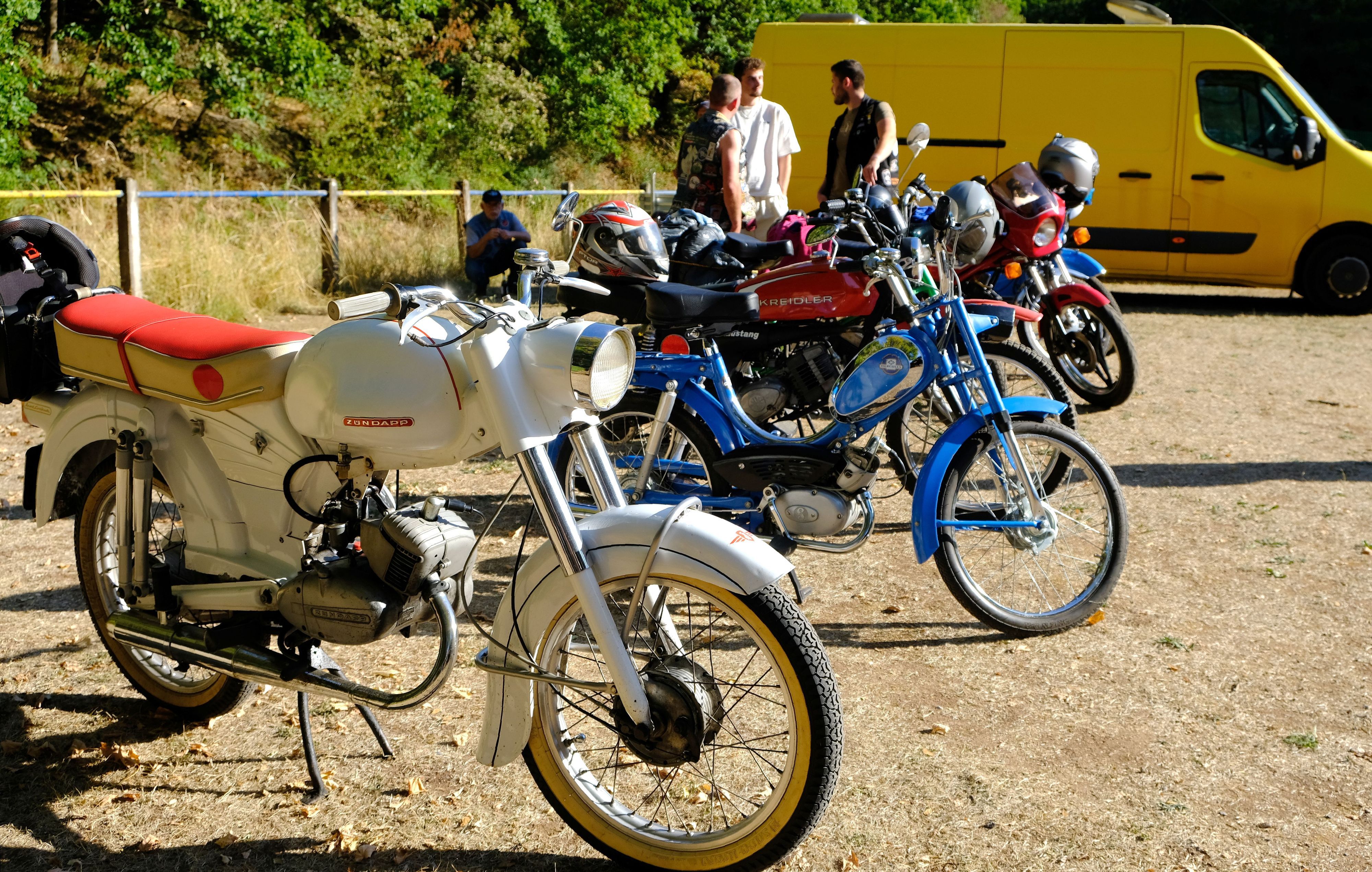 Auf dem Sportplatz in Vussem sind einige ältere Mopeds und Mofas in Reihe geparkt.