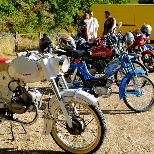 Auf dem Sportplatz in Vussem sind einige ältere Mopeds und Mofas in Reihe geparkt.