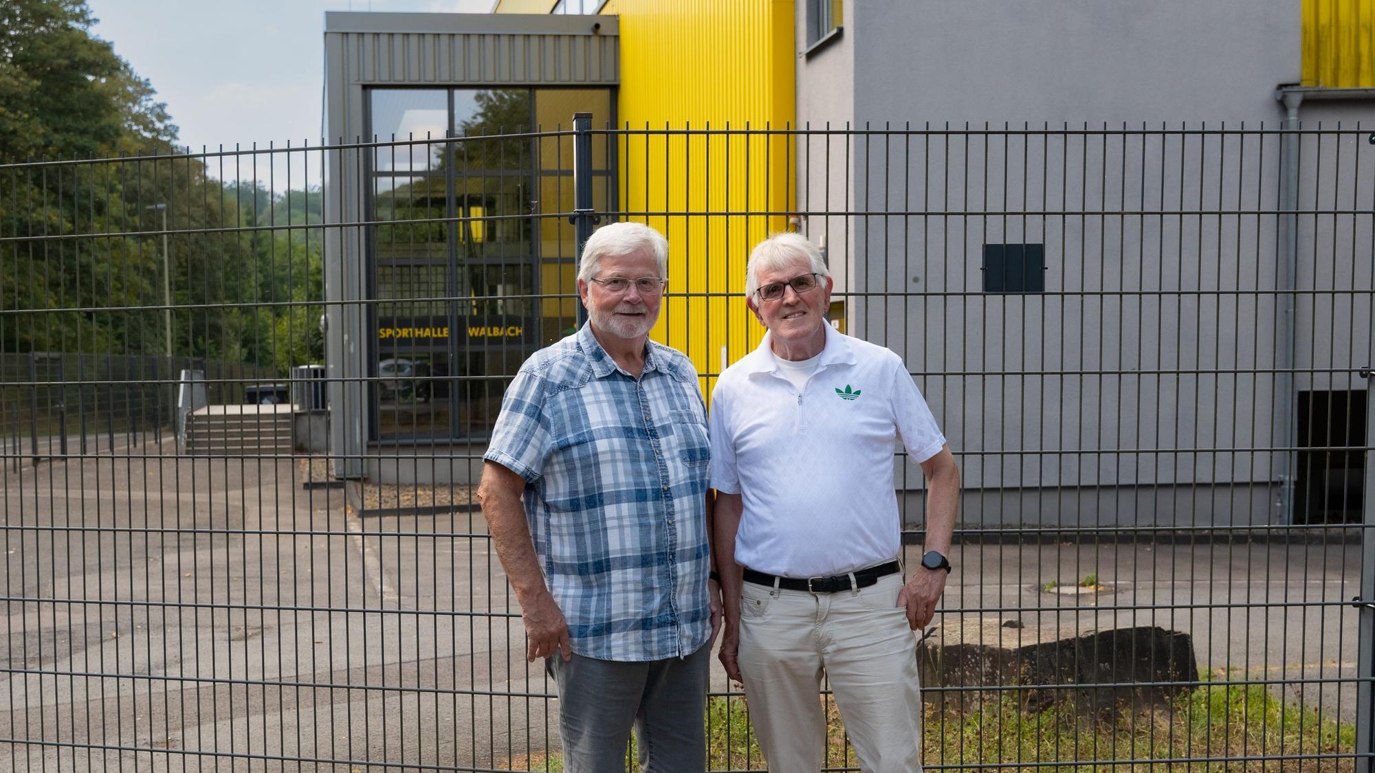 Die beiden Männer stehen vor dem Eingang der Halle.