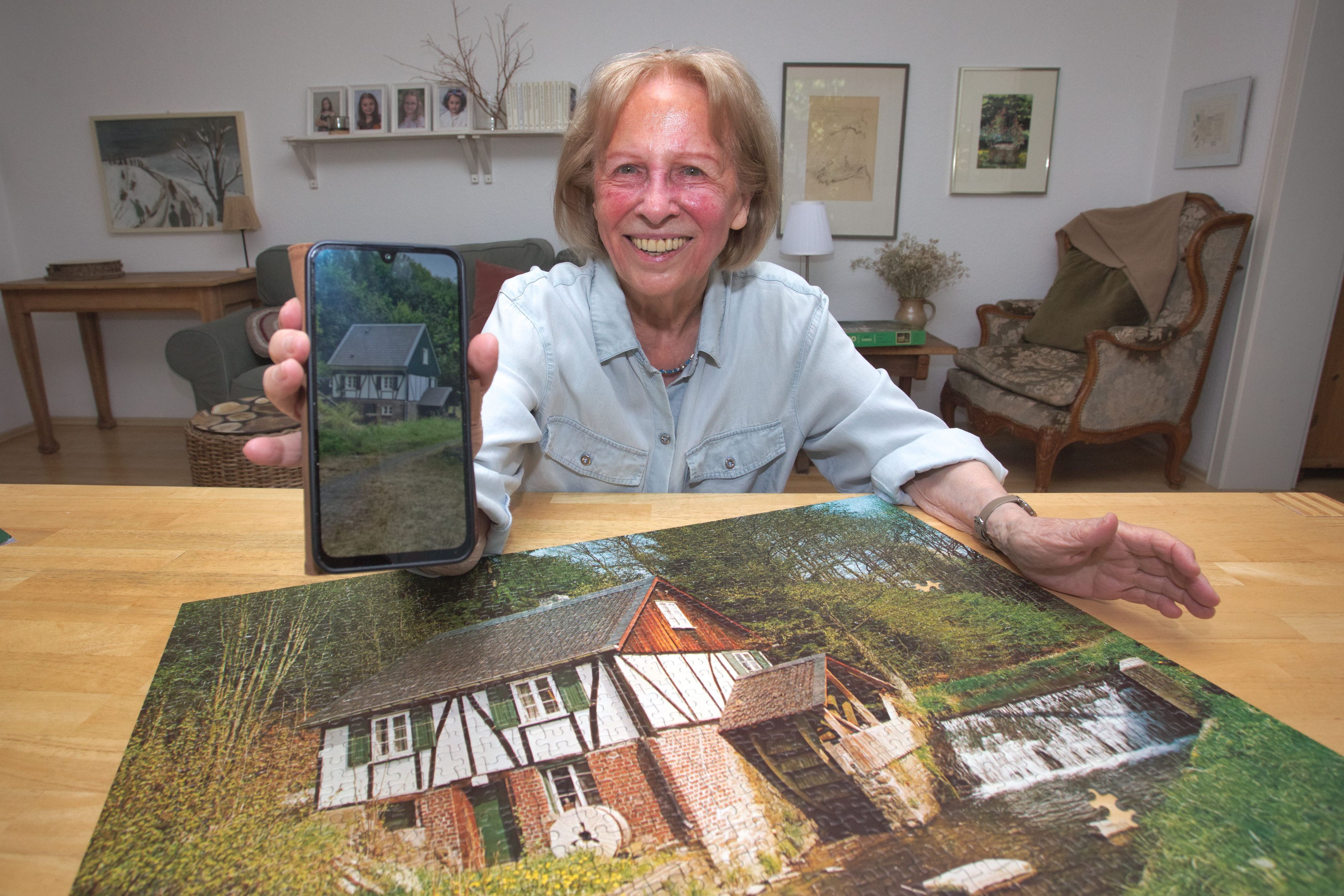 Zu sehen ist eine Frau mit Handy, davor ein Puzzle.