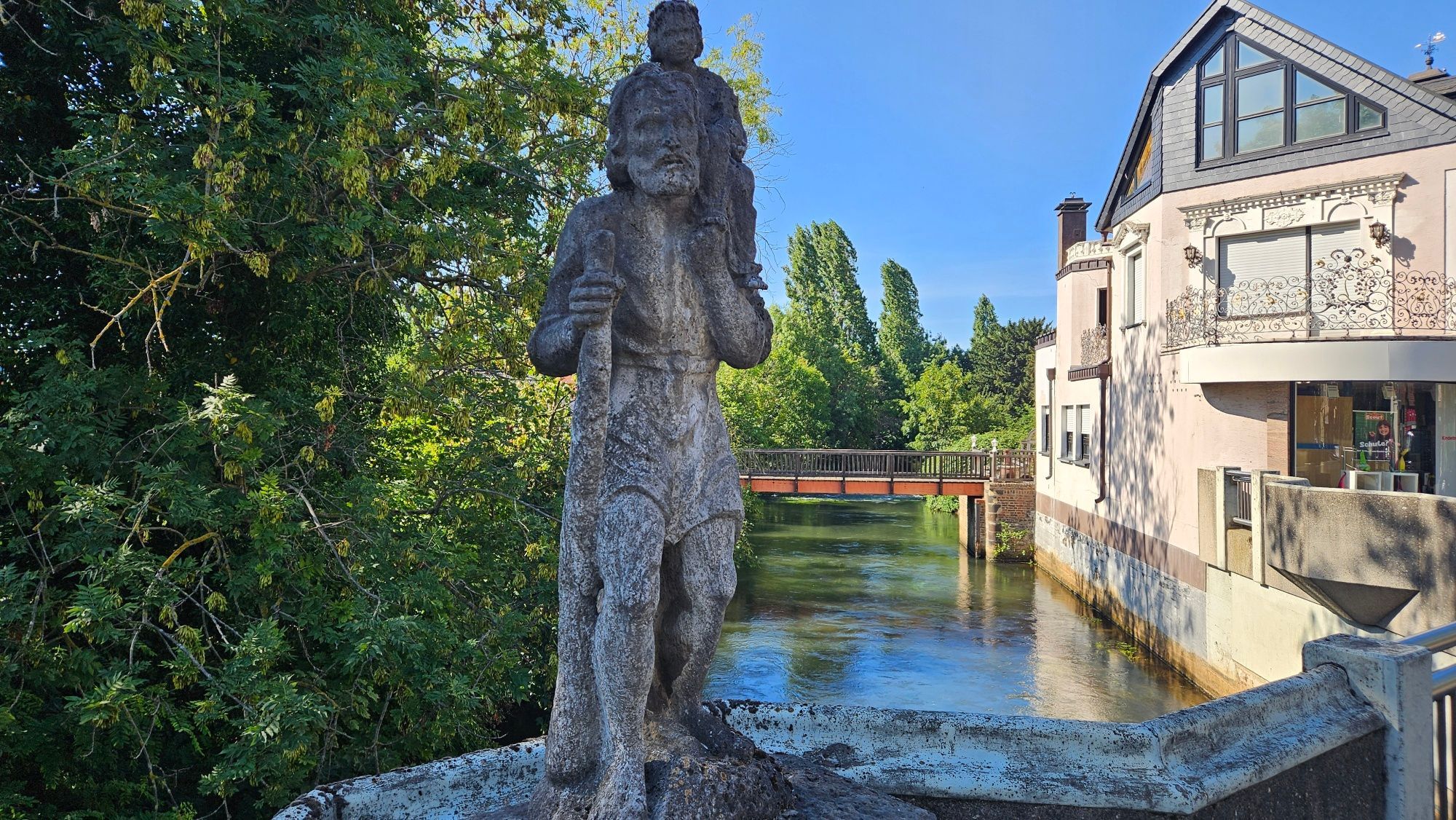Auf dem Bild ist eine Statue auf einer Brücke über einen Fluss zu sehen.