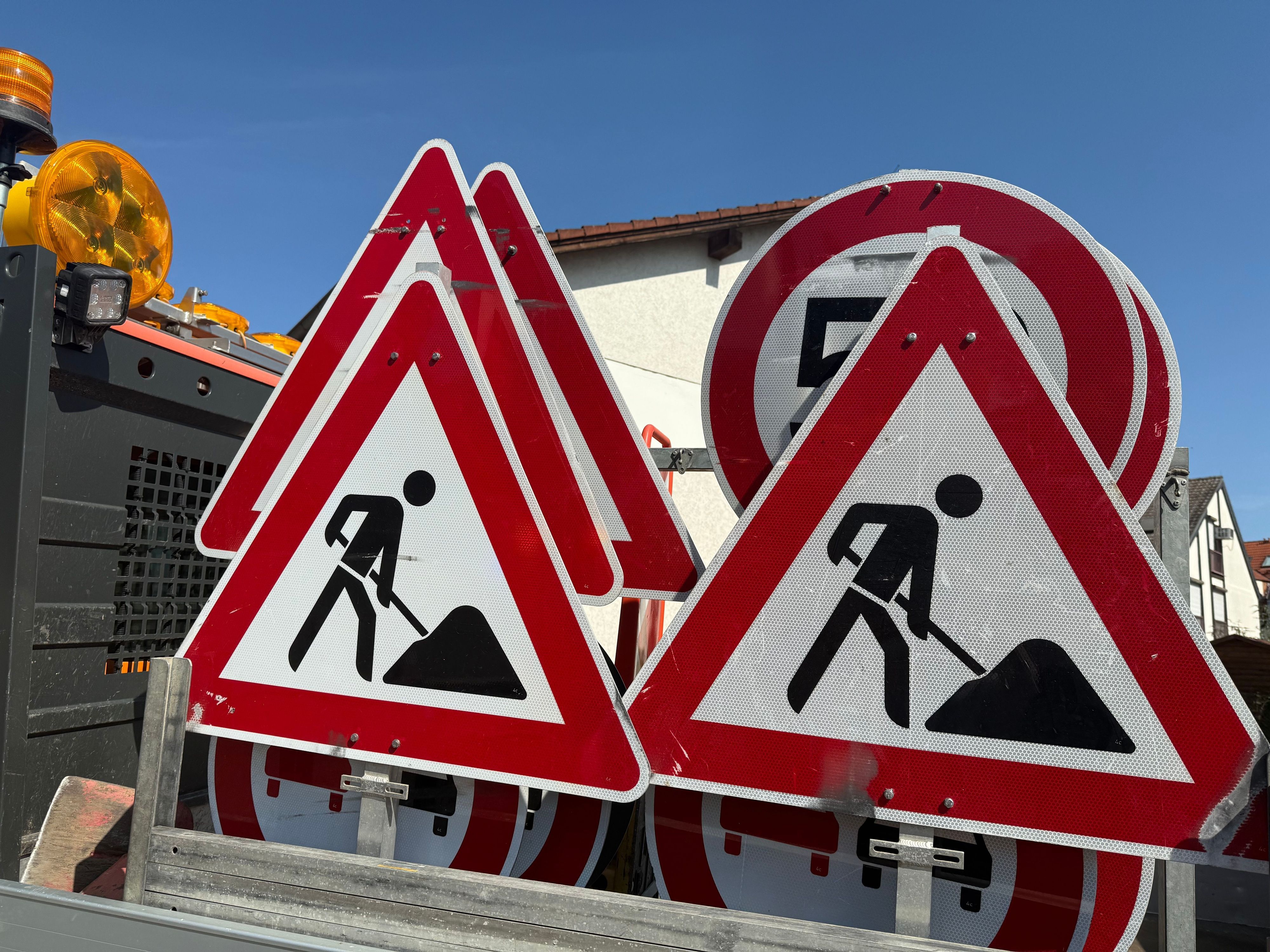 Mehrere Verkehrsschilder, die vor einer Baustelle warnen, stehen auf der Pritsche eines Transporters. (Symbolbild)