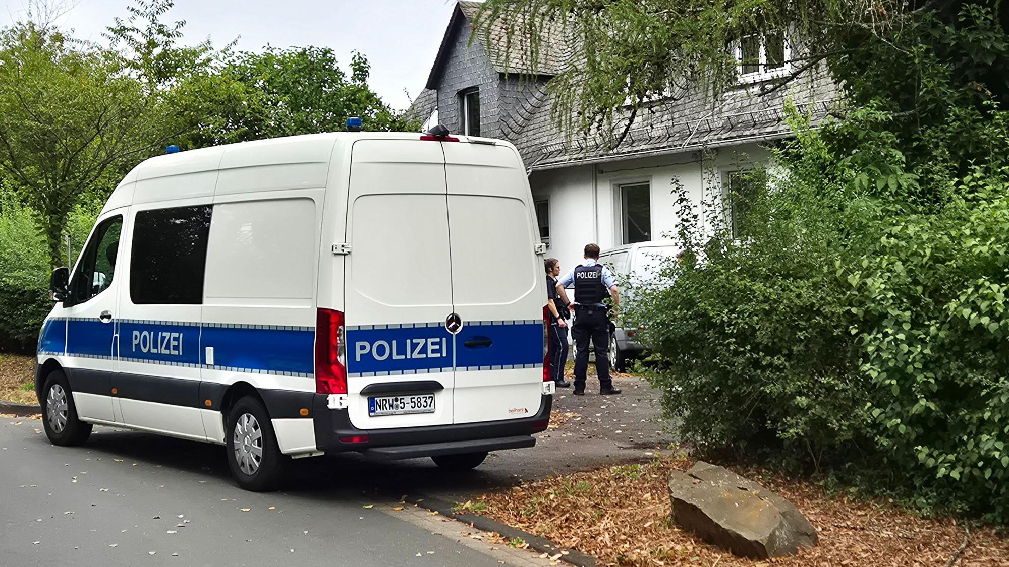 Einsatzkräfte der Polizei stehen vor einem Wohnhaus in Siegen. Dort wurden die Leichen entdeckt.