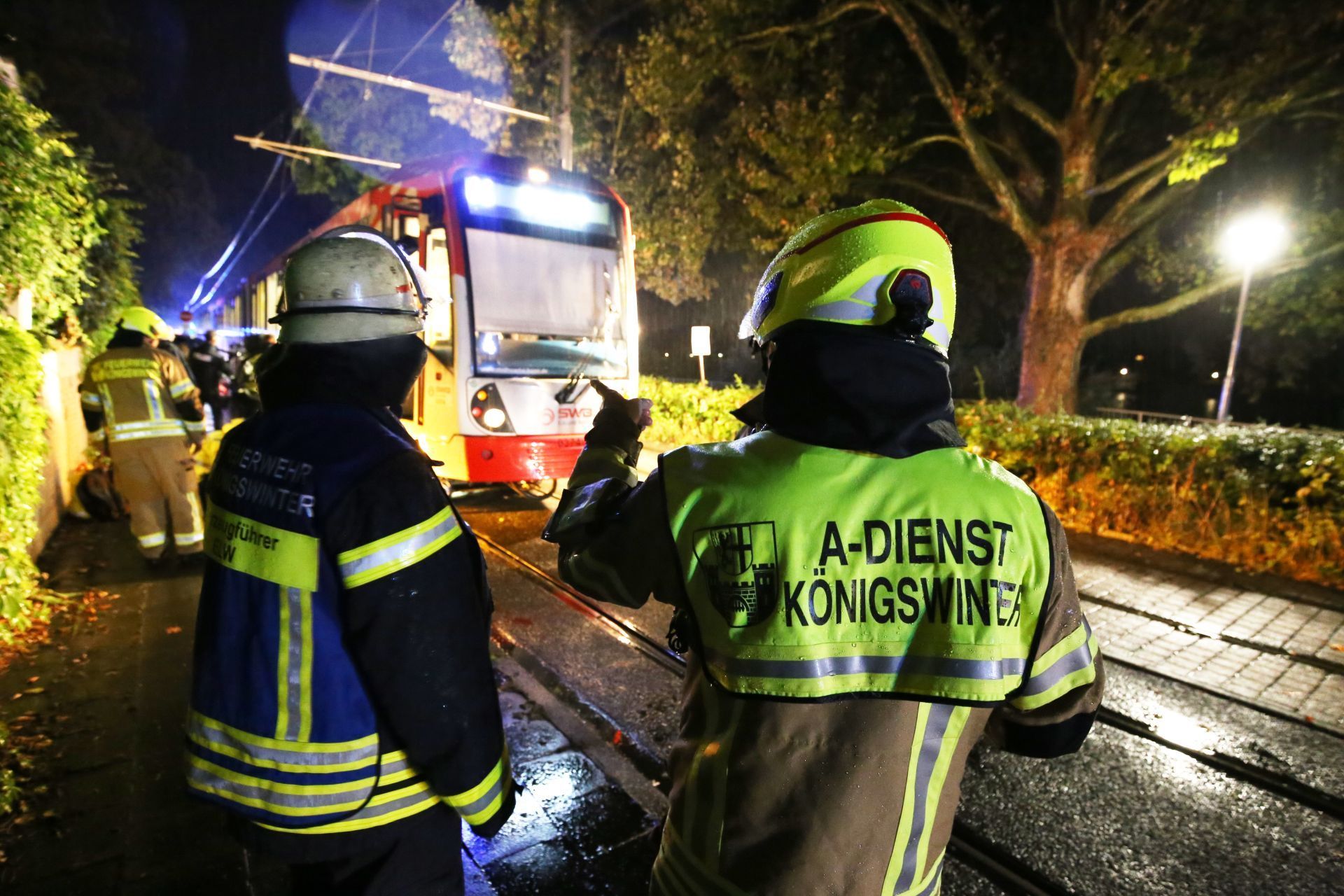 Feuerwehrleute stehen vor einer Straßenbahn, unter der ein Fahrrad eingeklemmt ist.