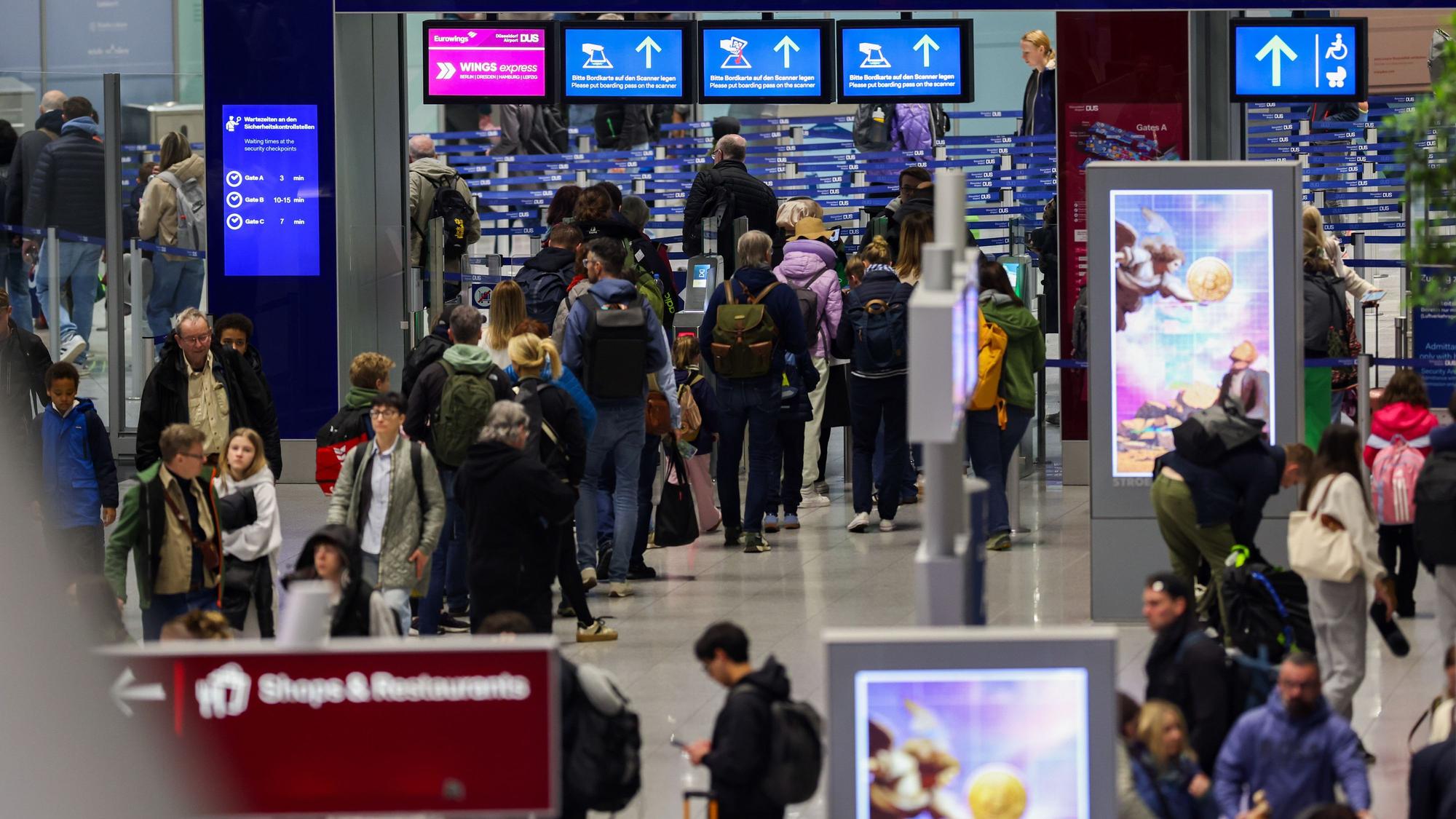 Reisende gehen in Richtung der Gates am Flughafen in Düsseldorf (Archivfoto).