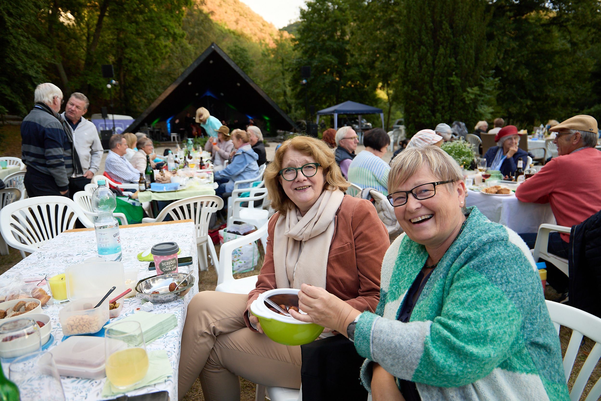 Die beiden Frauen sitzen an einem gedeckten Picknicktisch inmitten anderer Besucher.