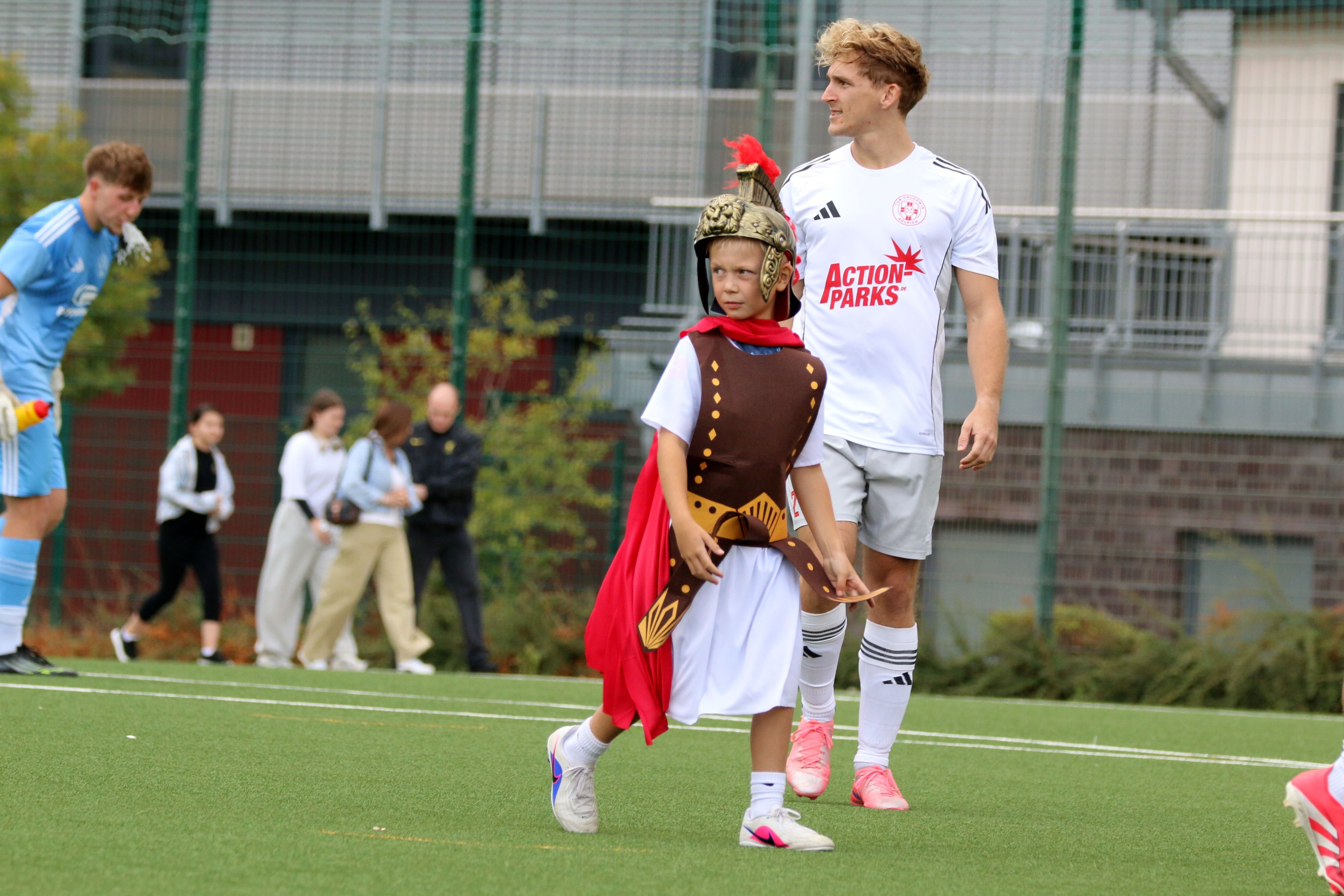 Ein Kind ist als Legionär verkleidet und geht über den Fußballplatz.