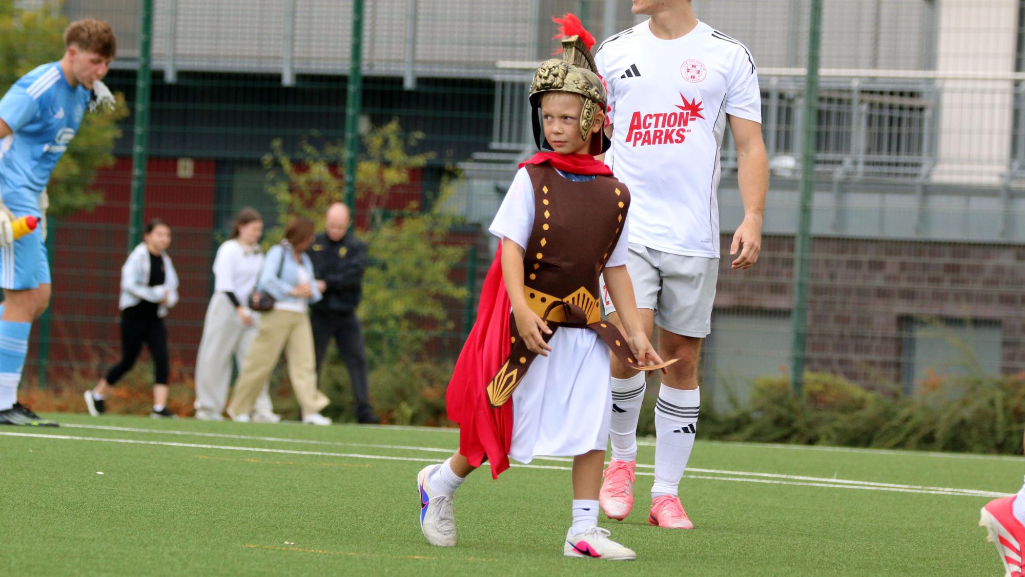 Ein Kind ist als Legionär verkleidet und geht über den Fußballplatz.