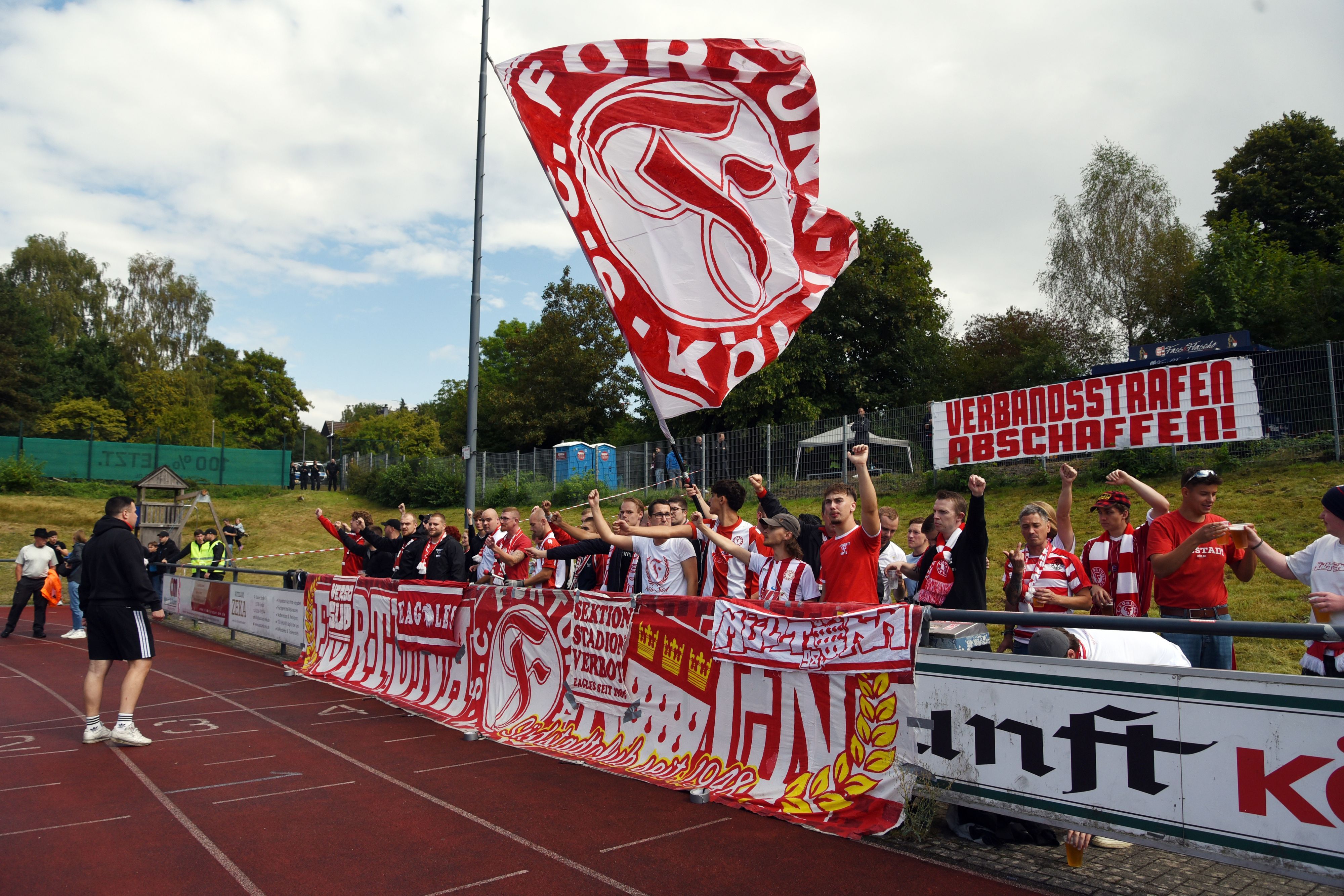 Fans mit Bannern und Fahne am Rande eines Fußballspiels