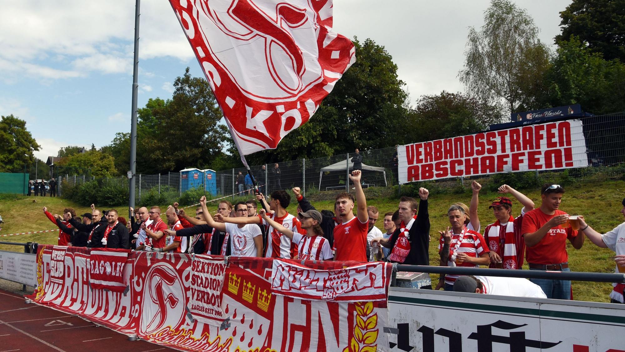 Fans mit Bannern und Fahne am Rande eines Fußballspiels