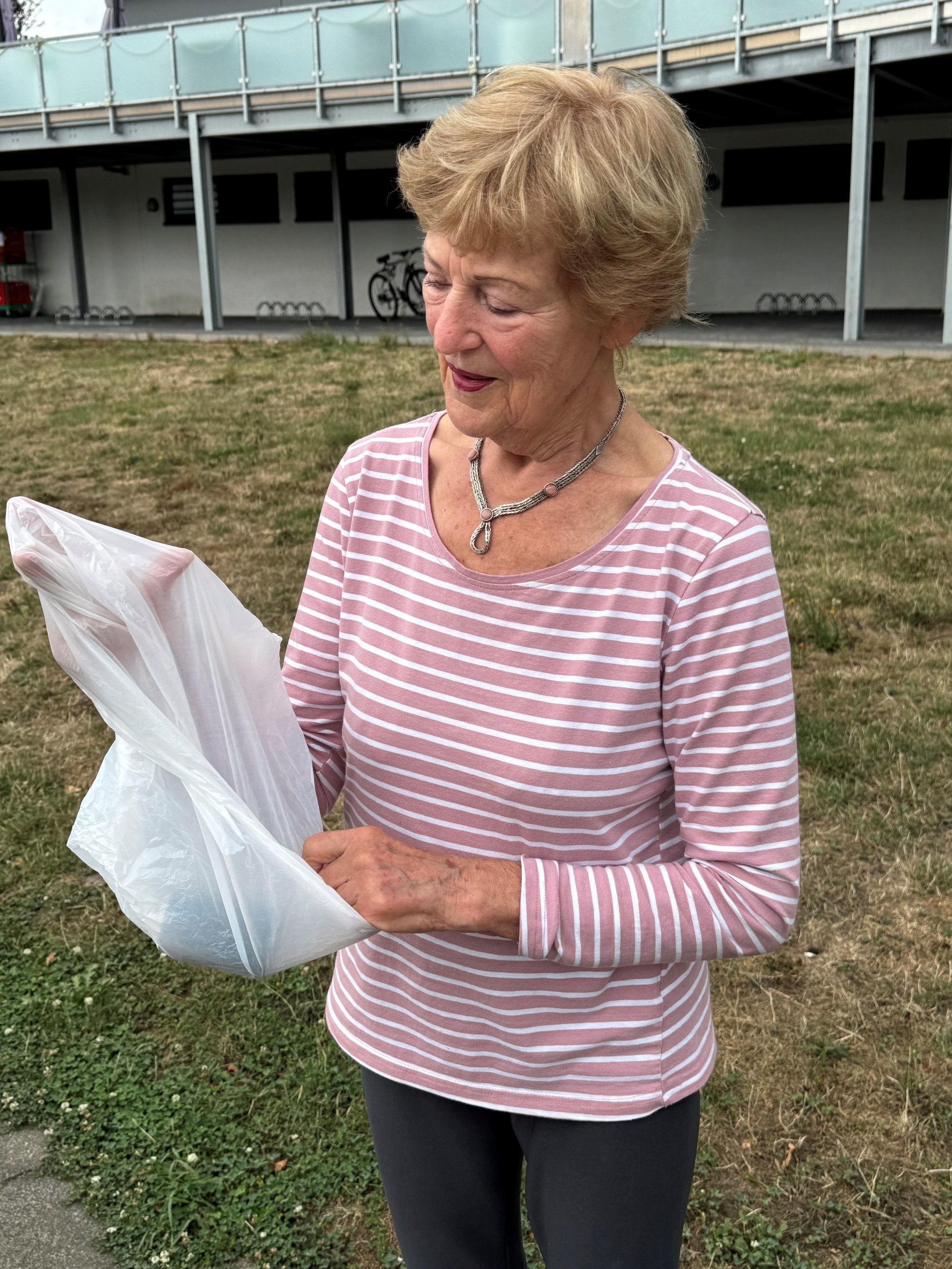 Das Foto zeigt eine Frau mit einer Mülltüte in der Hand.