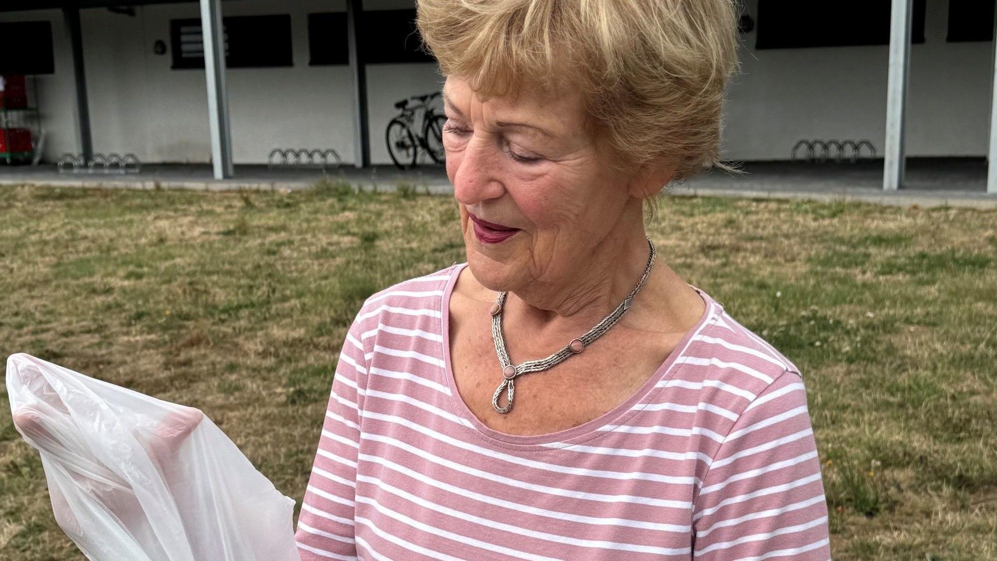 Das Foto zeigt eine Frau mit einer Mülltüte in der Hand.