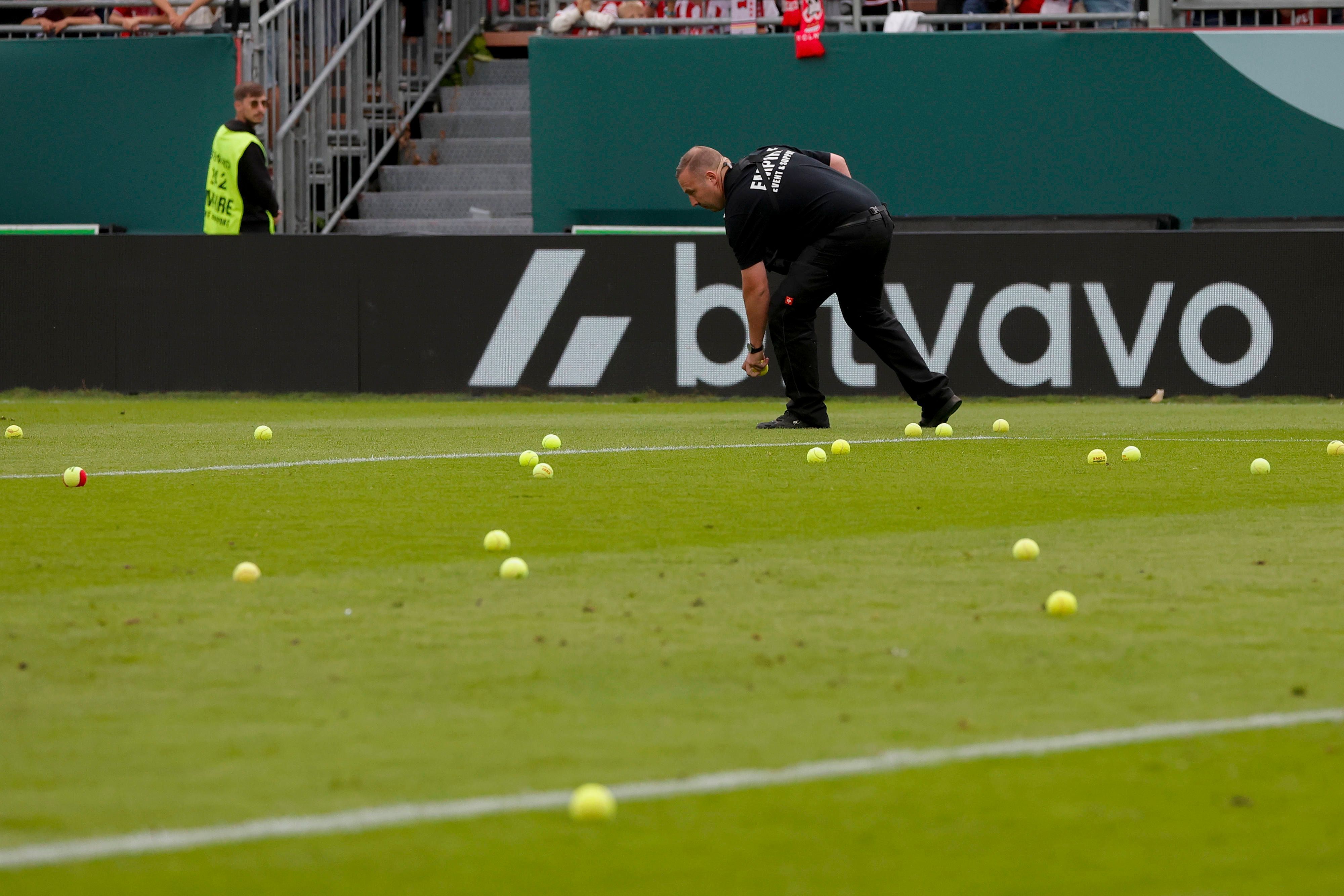 Ein Ordner sammelt Tennisbälle auf.
