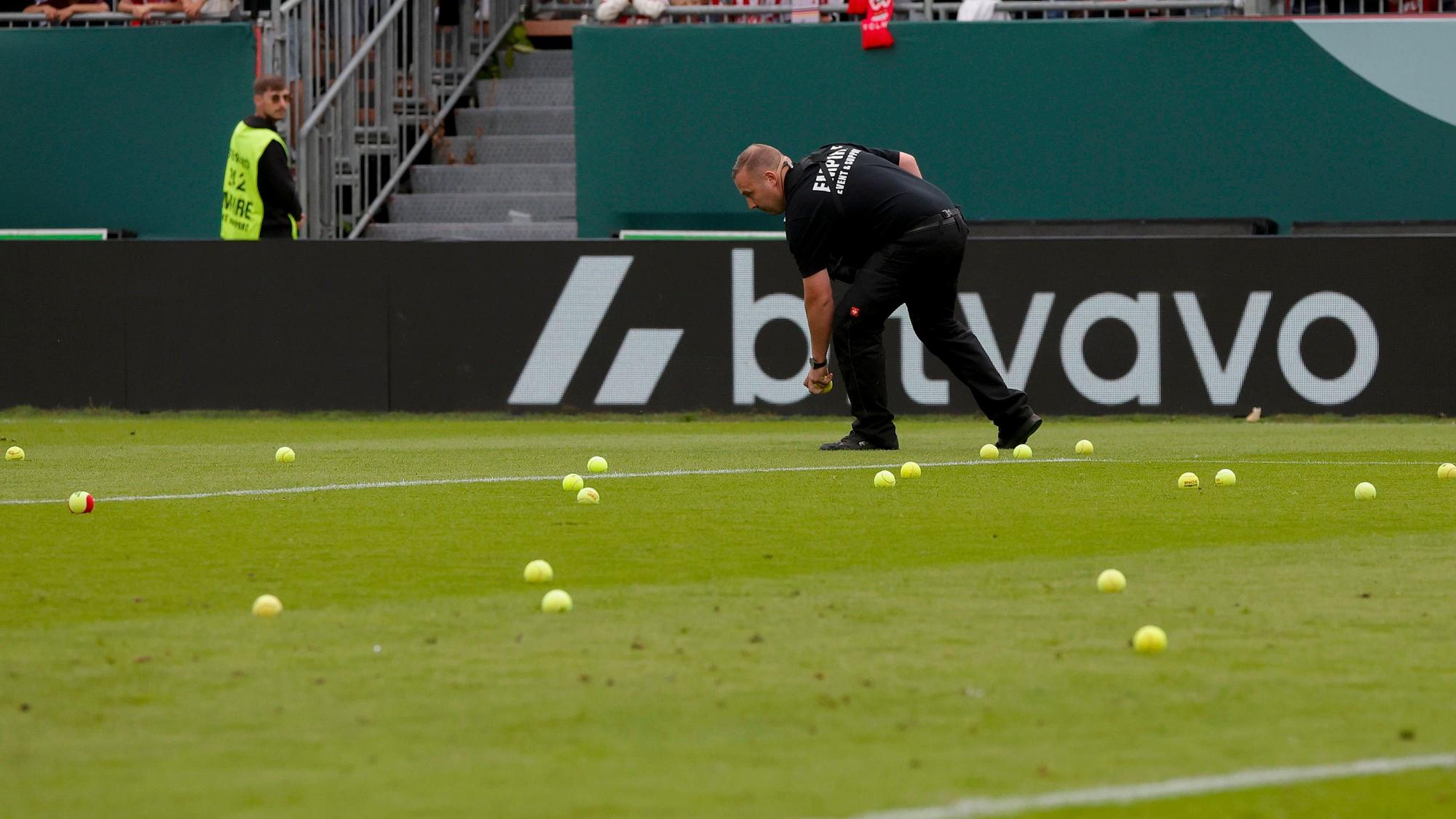 Ein Ordner sammelt Tennisbälle auf.