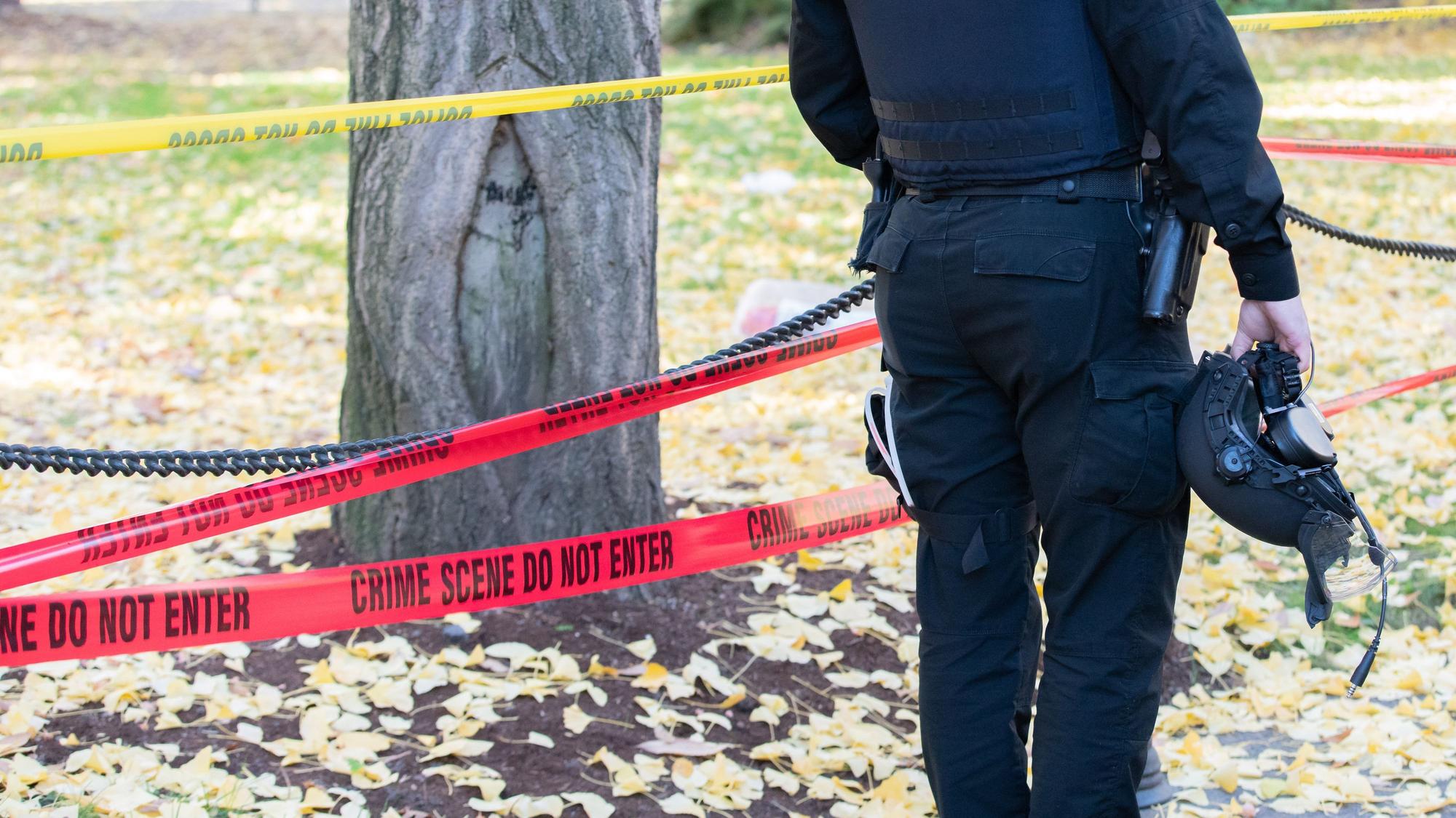 Polizist mit Helm, der am Tatort steht.