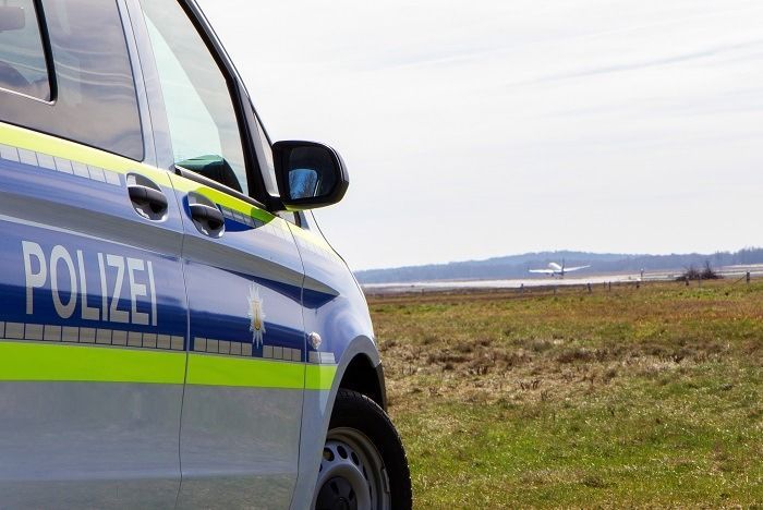 Ein Streifenwagen und ein Hubschrauber der Bundespolizei auf einem Flugfeld.