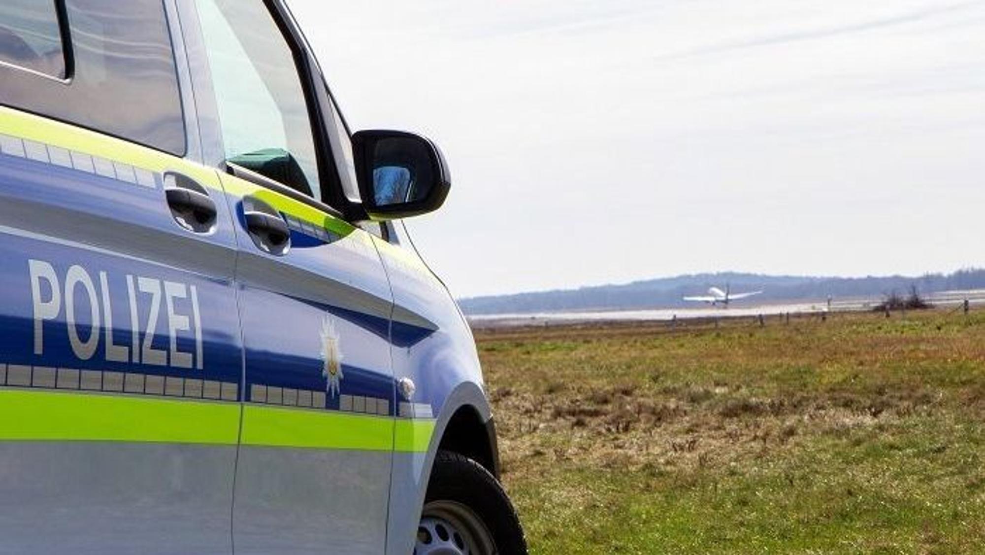 Ein Streifenwagen und ein Hubschrauber der Bundespolizei auf einem Flugfeld.