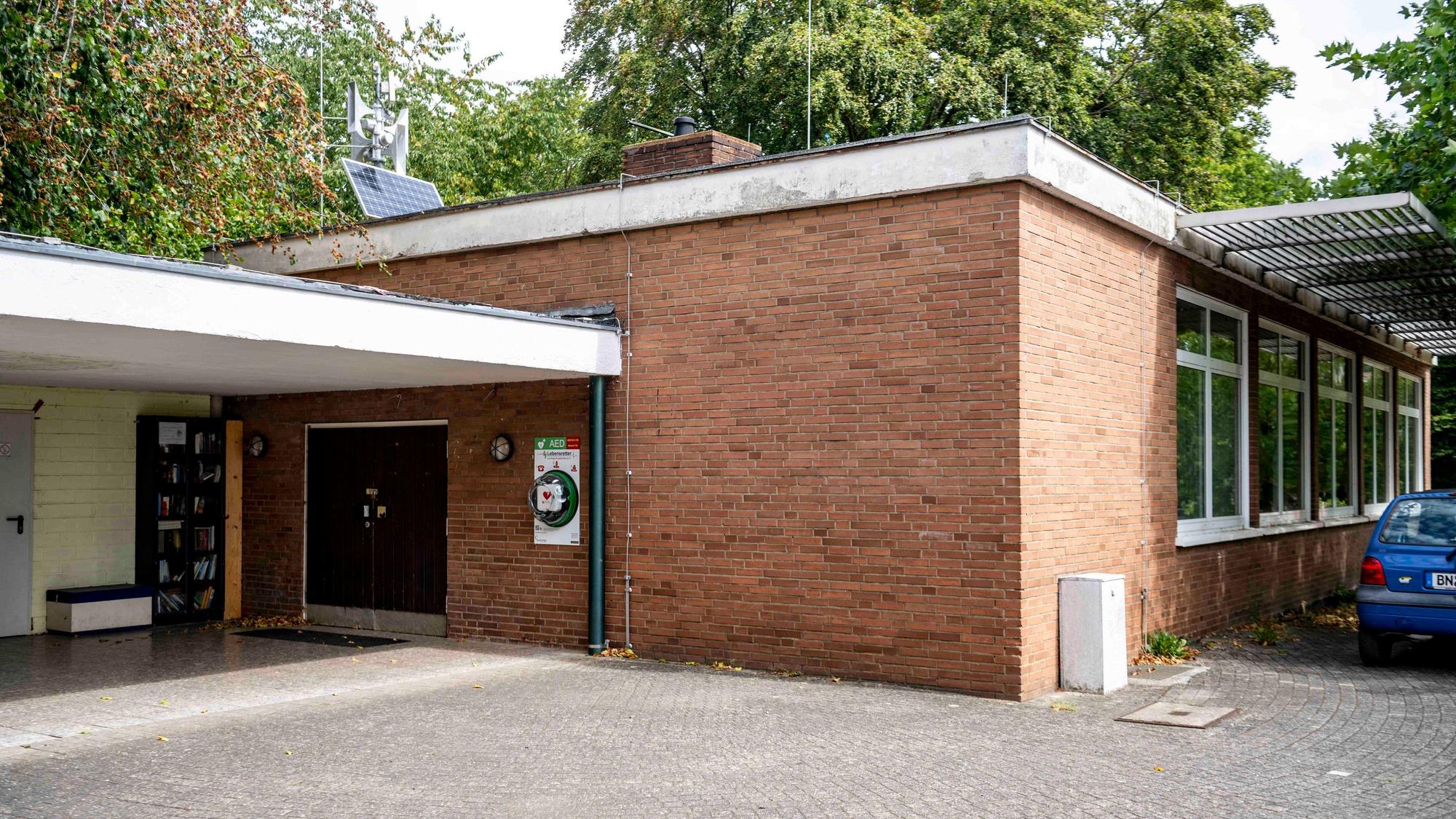 Das Dorfgemeinschaftshaus ist ein Flachbau, der Eingang ist überdacht. Hinter dem Gebäude stehen Bäume.