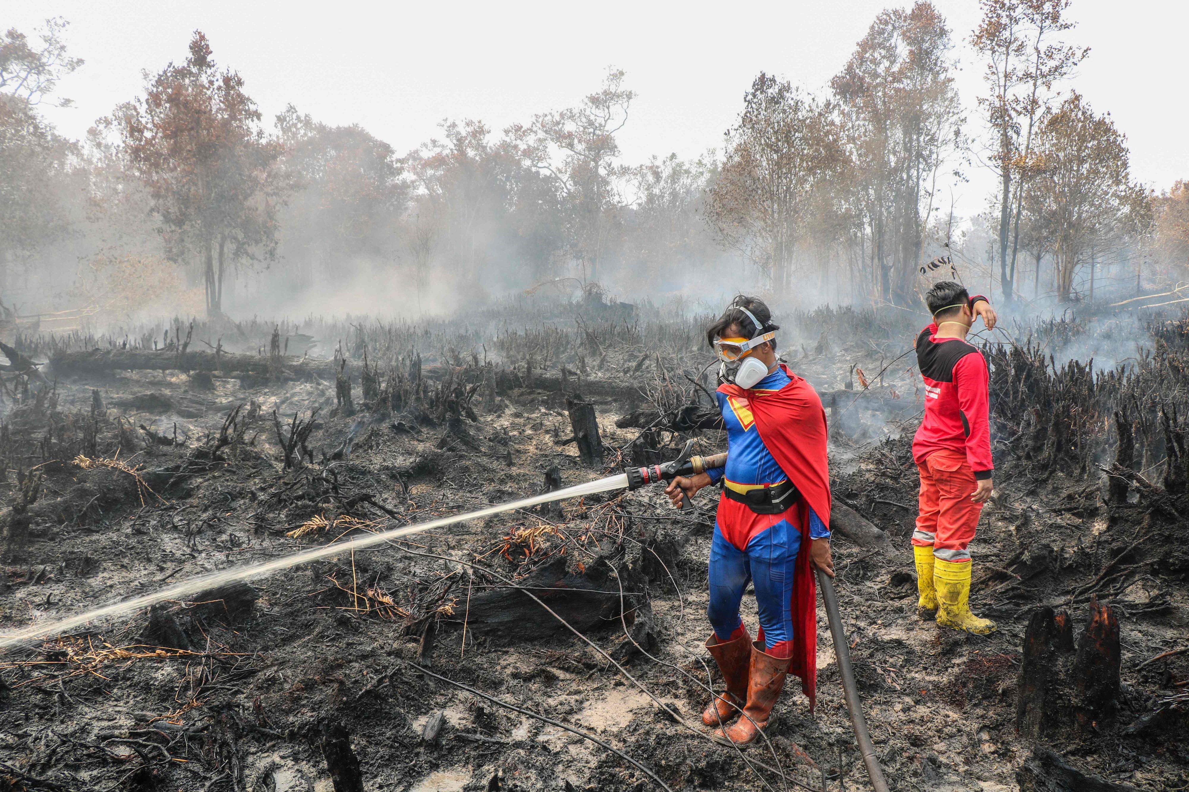 Der Student Rudiansyah (L) trägt ein Superman-Kostüm während des Löscheinsatzes.