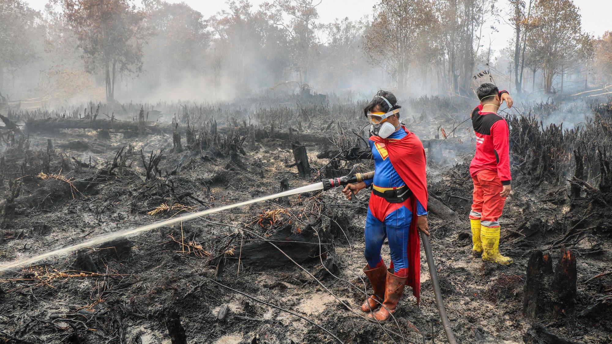 Der Student Rudiansyah (L) trägt ein Superman-Kostüm während des Löscheinsatzes.