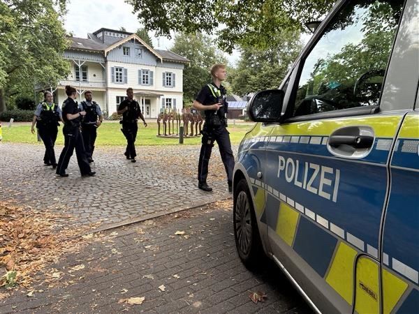 Mehrere Polizeikräfte gehen auf einen Streifenwagen zu.
