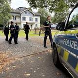 Mehrere Polizeikräfte gehen auf einen Streifenwagen zu.
