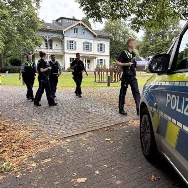 Mehrere Polizeikräfte gehen auf einen Streifenwagen zu.