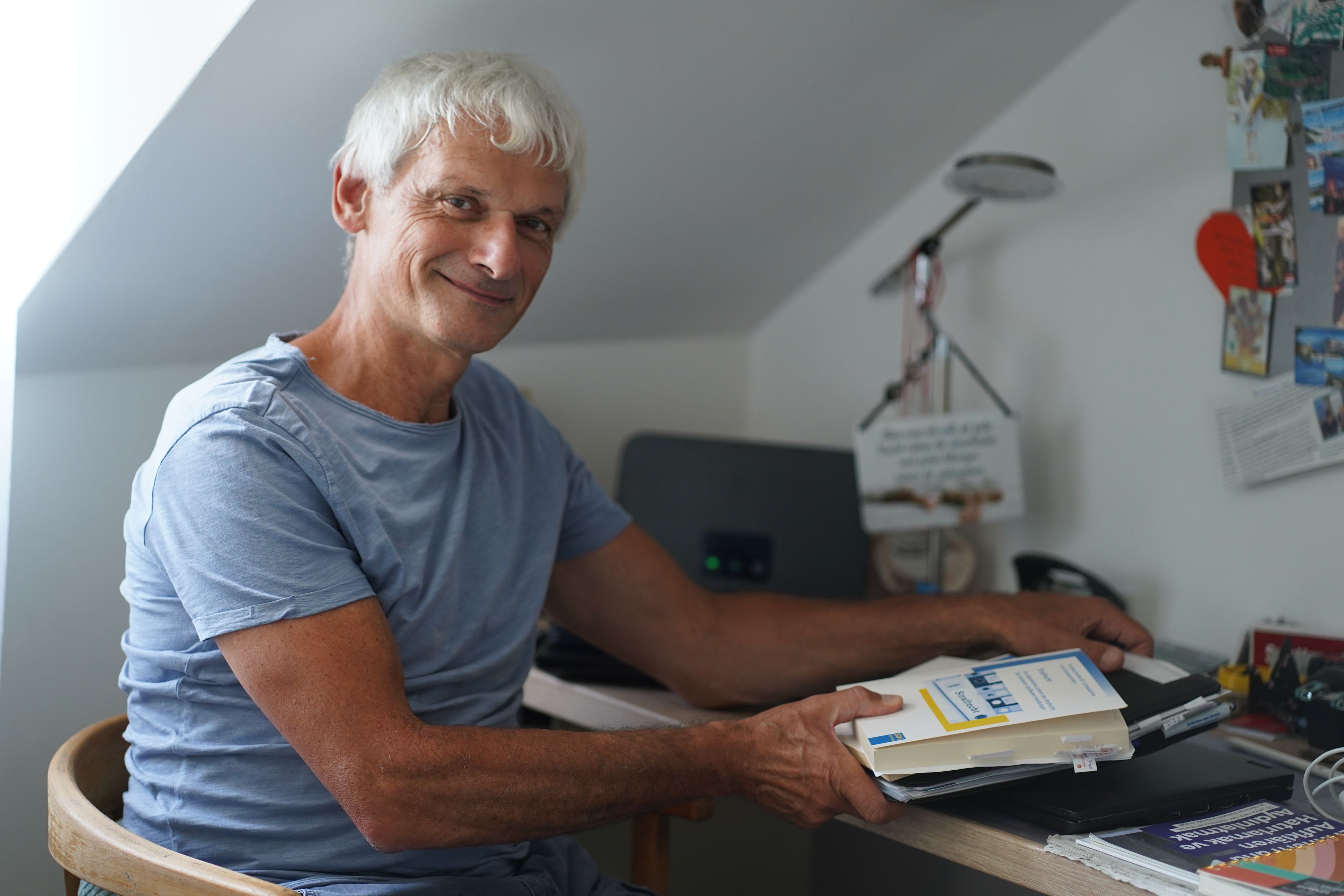 Das Foto zeigt einen Mann an einem Schreibtisch, der Bücher in den Händen hält.