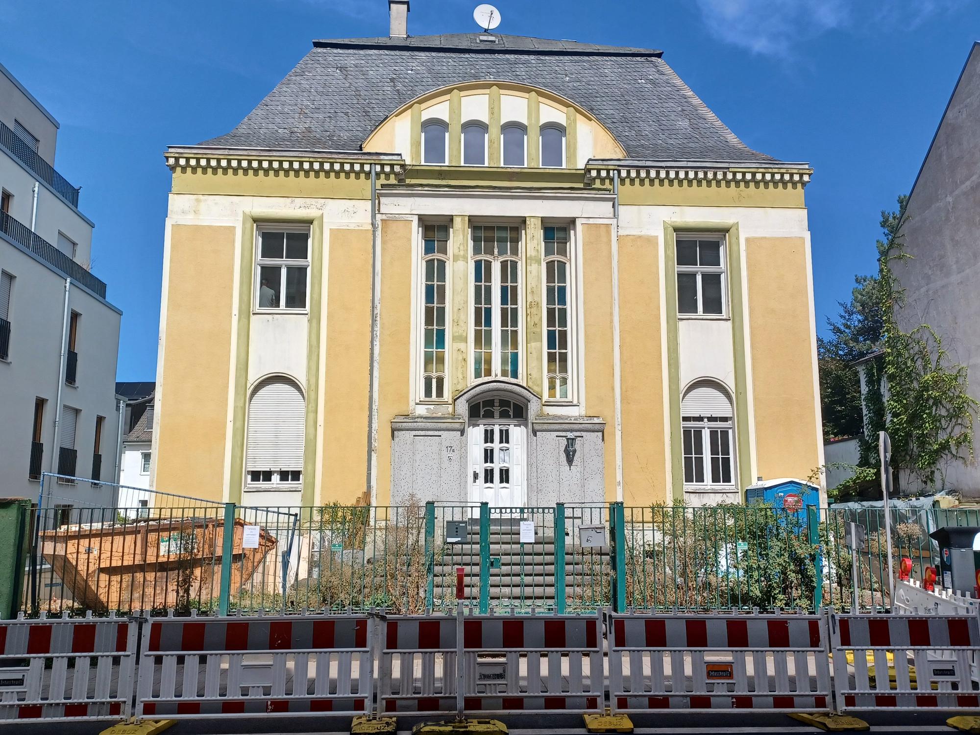 Auf dem Grundstück einer herrschaftlichen Villa stehen Baucontainer und ein Dixi-Klo.