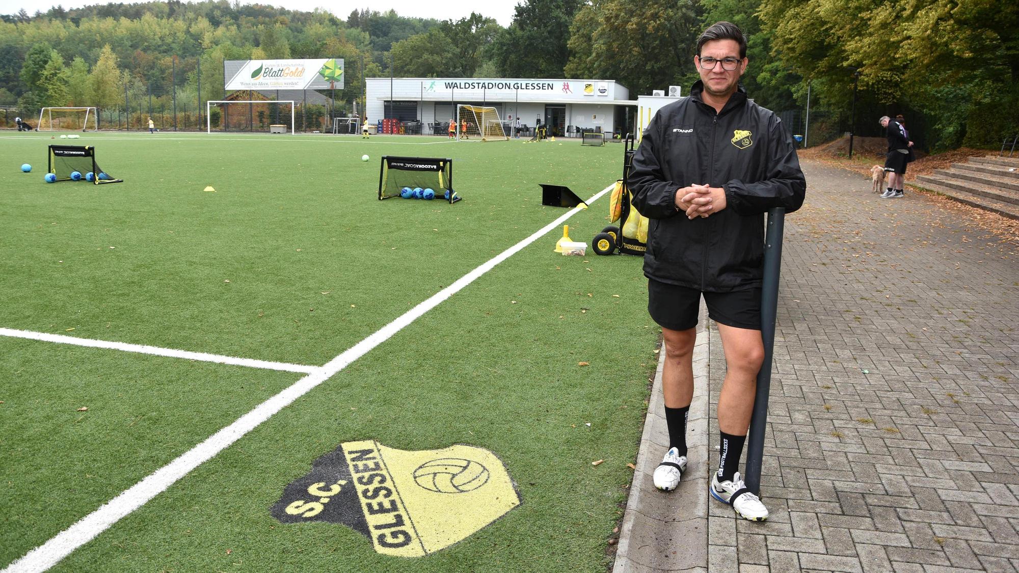 Ein Mann steht neben der Seitenlinie eines Fußballplatzes.