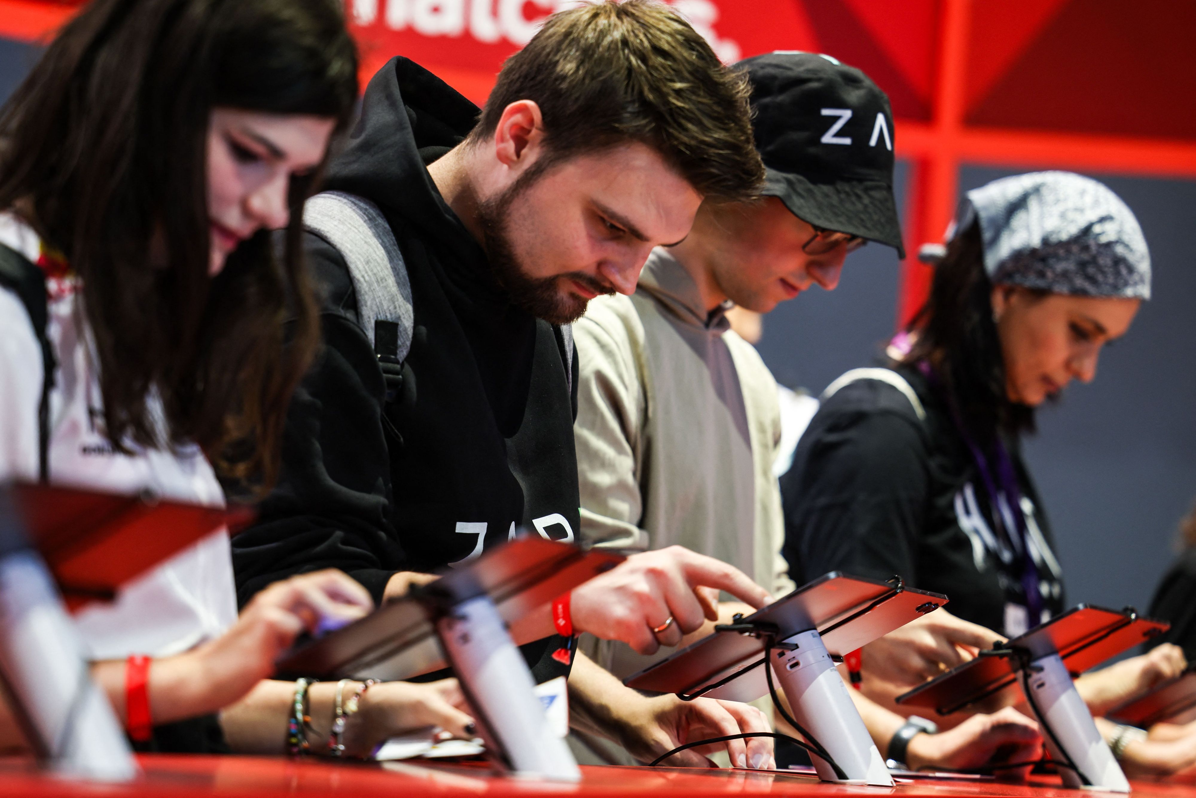 Besucher der Messe Gamescom stehen an Tablets und spielen ein Videospiel.