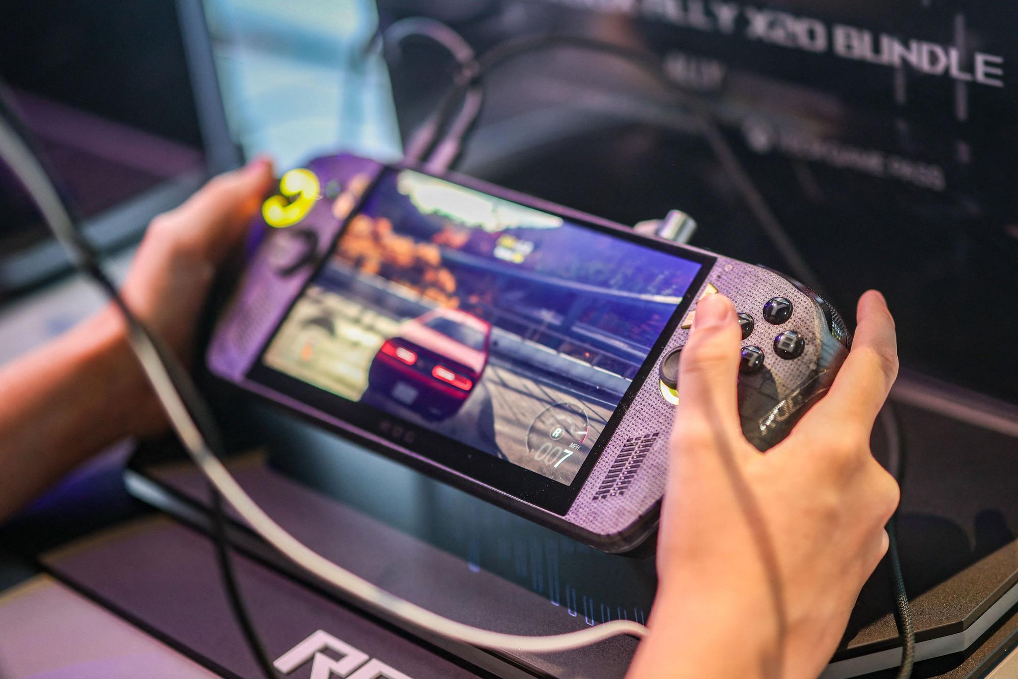 Ein Besucher der Messe Gamescom spielt ein Videospiel auf einer kleinen Konsole.
