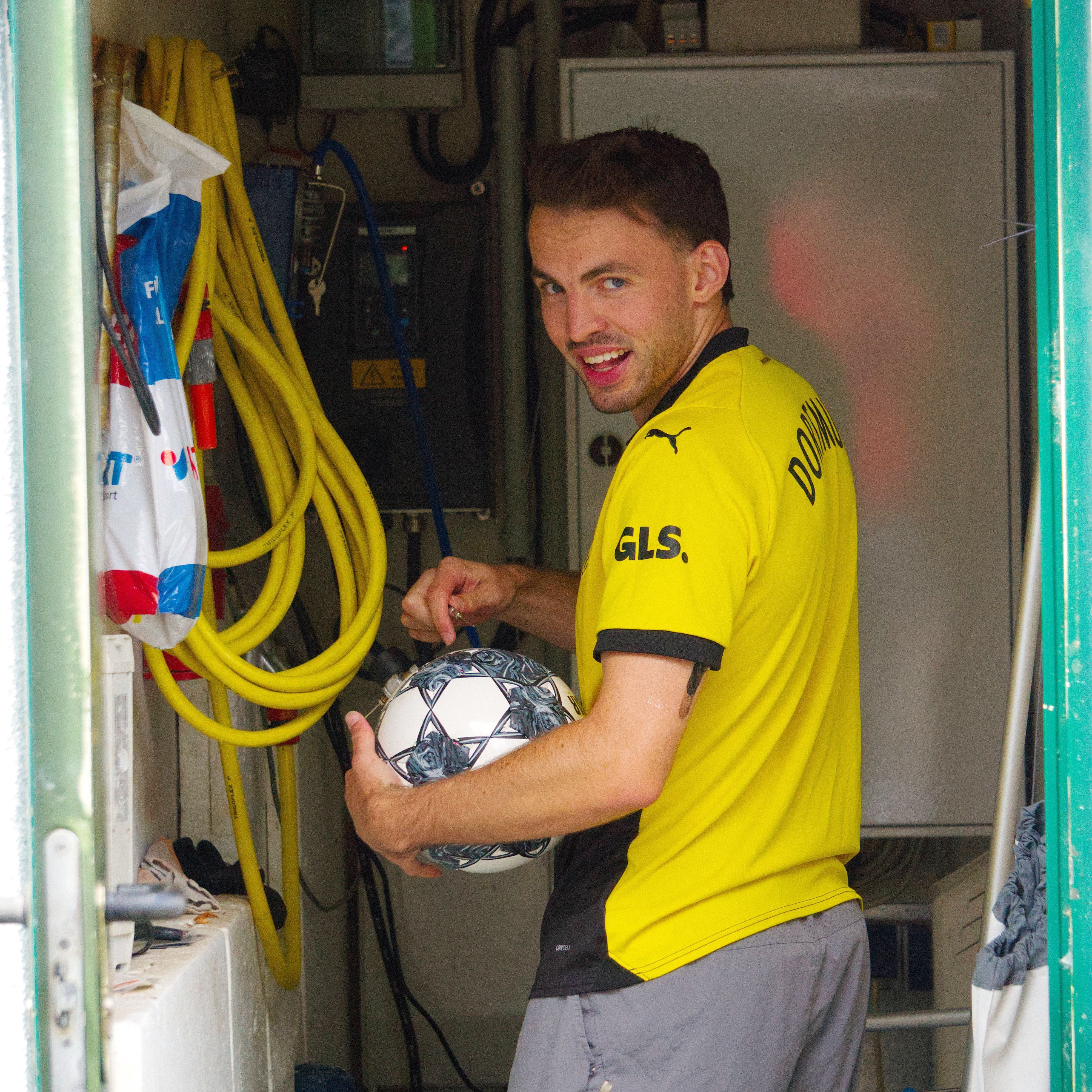 Tom Thiele trägt ein Dortmund-Trikot und hält einen Fußball im Arm.