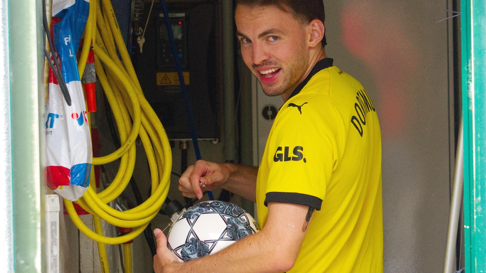 Tom Thiele trägt ein Dortmund-Trikot und hält einen Fußball im Arm.