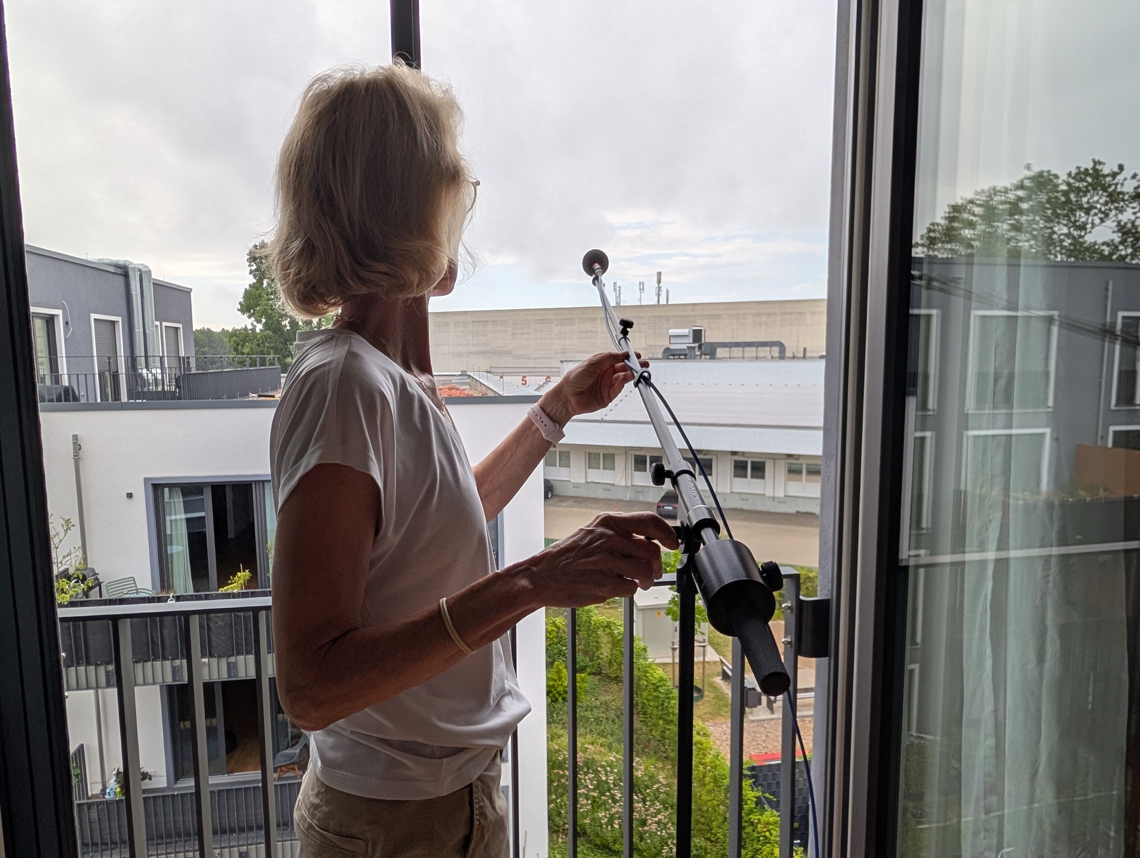 Das Foto zeigt die Anwohnerin mit einem Lärmmessgerät an ihrem Fenster.